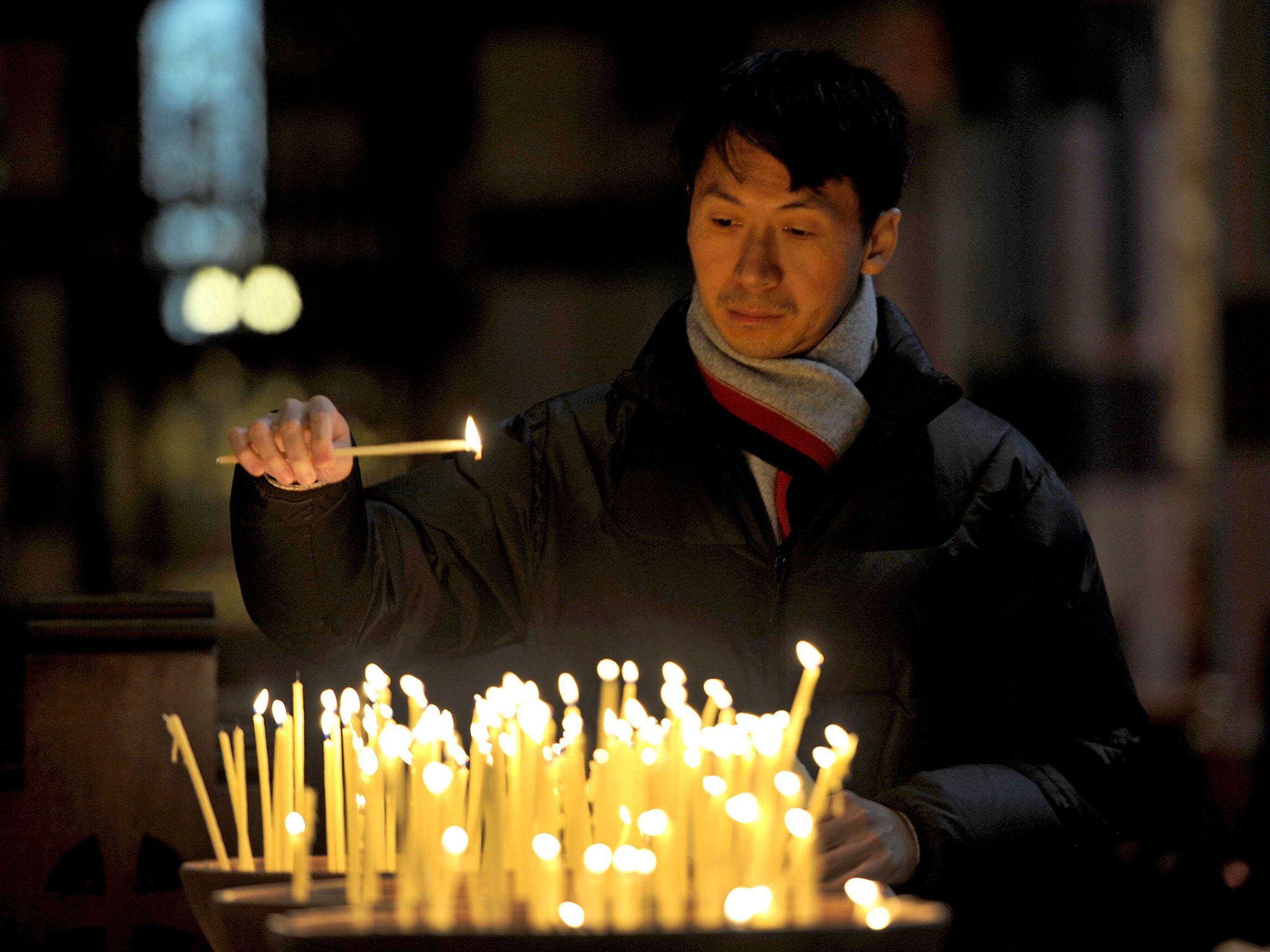 A man lights a candle as family and friends attend a multi-faith service at St. Paul's Cathedral in Melbourne for those who lost their lives on Malaysia Airlines flight MH17