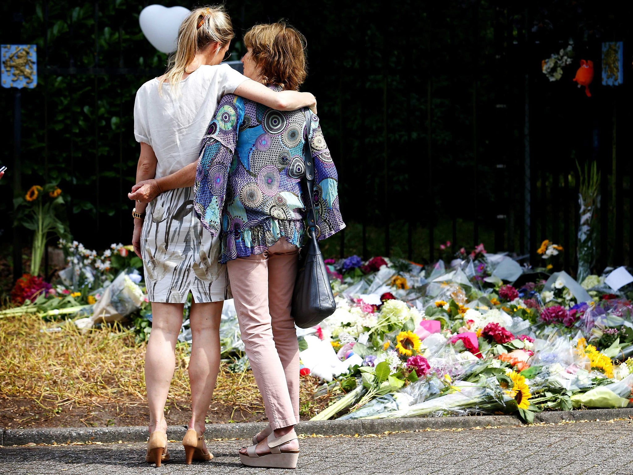 Sympathizers hug in front of flowers tribute at the entrance to the Korporaal van Oudheusdenkazerne, army barracks, in Hilversum, The Netherlands, where bodies of the people killed in the Malaysia Airlines MH17 air crash in Ukraine will be identified