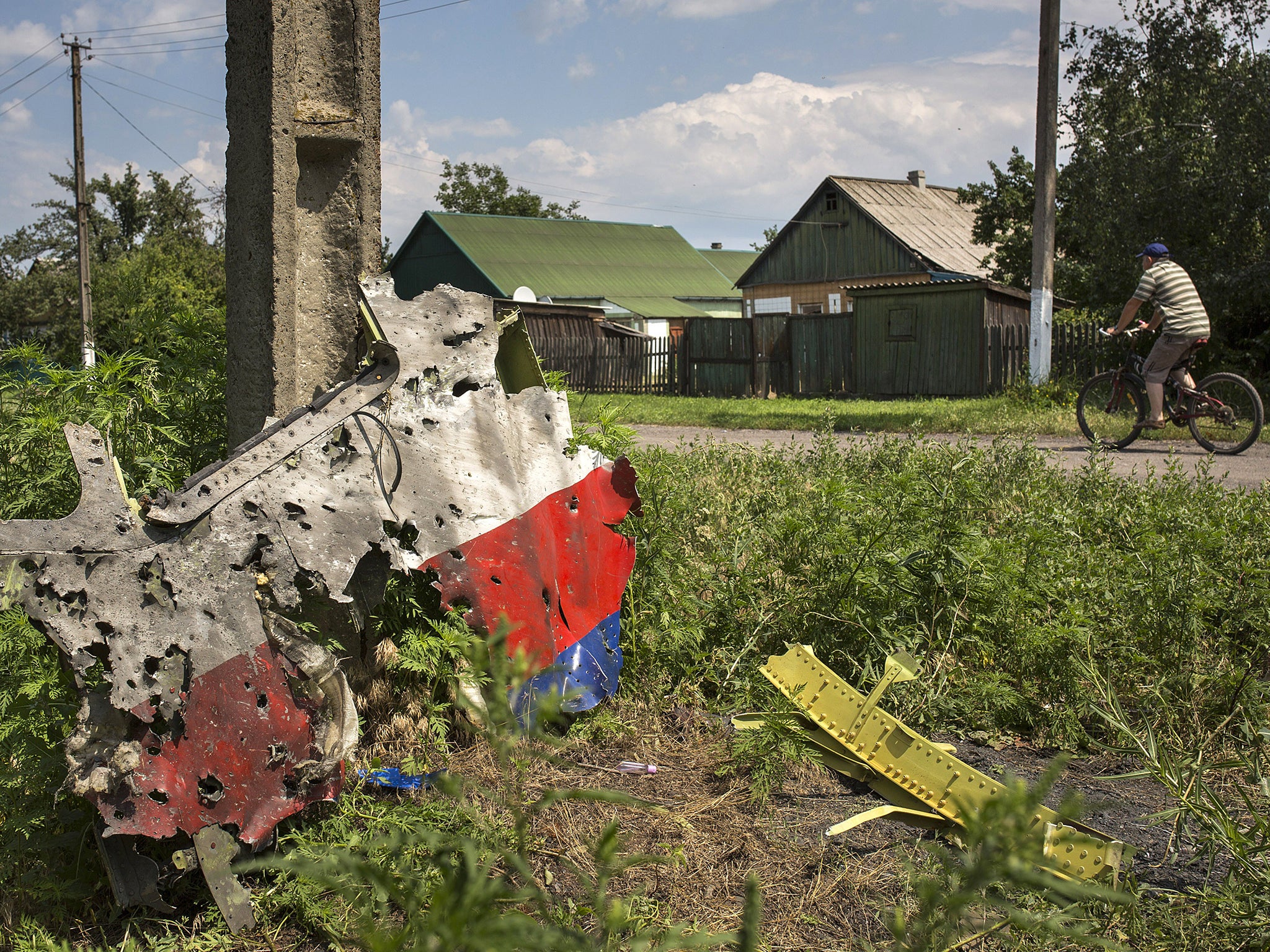 A man cycles past a piece of the wreckage of the Malaysia Airlines flight MH17 in Petropavlivka, Ukraine