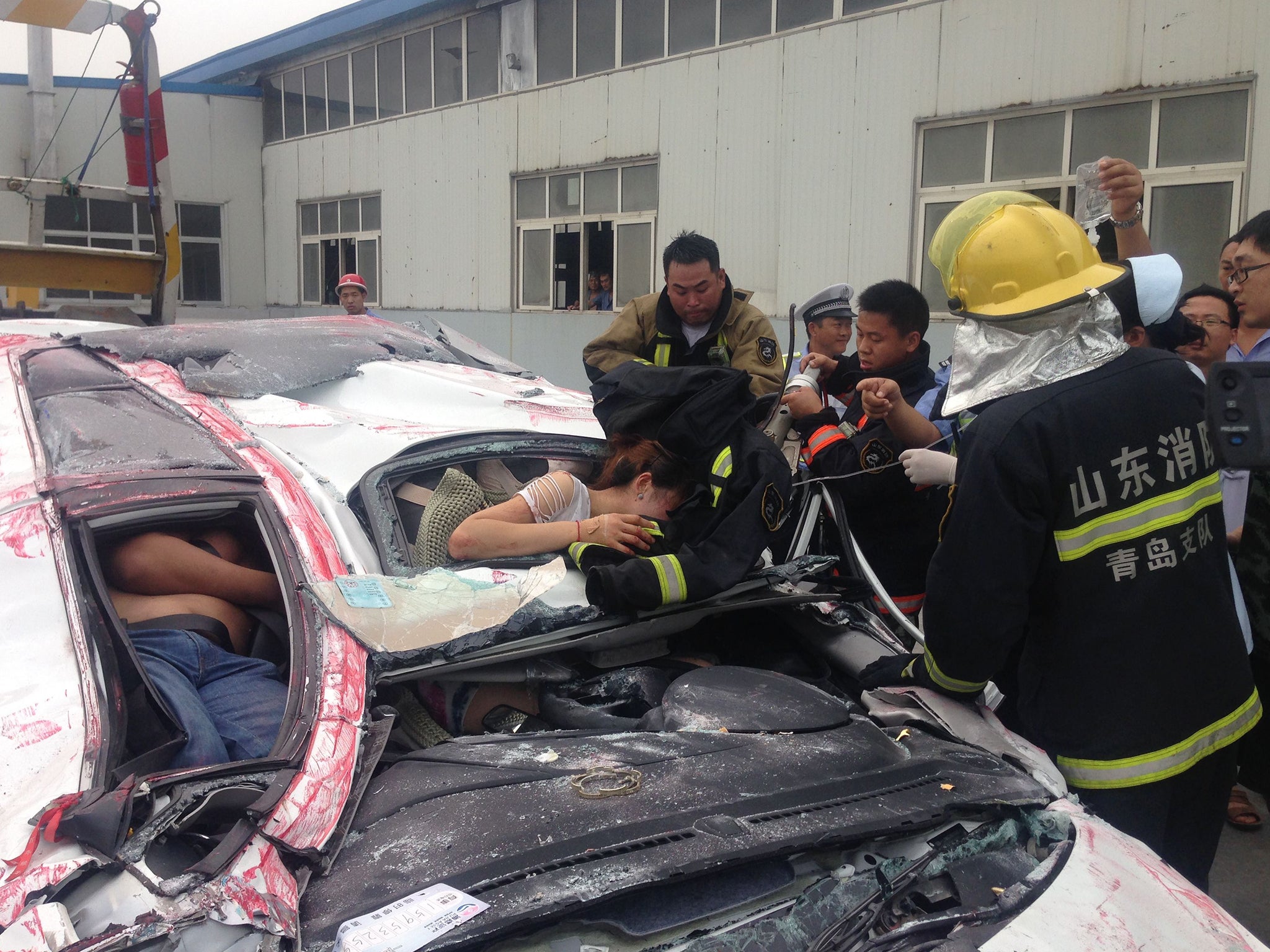 Firefighters work to free the woman from the flattened car