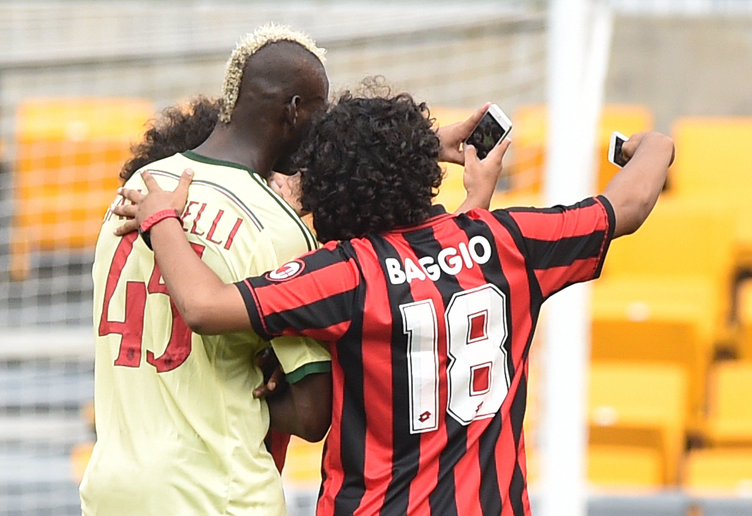 Mario Balotelli poses for a selfie with pitch invaders during Milan's 5-1 defeat to Manchester City