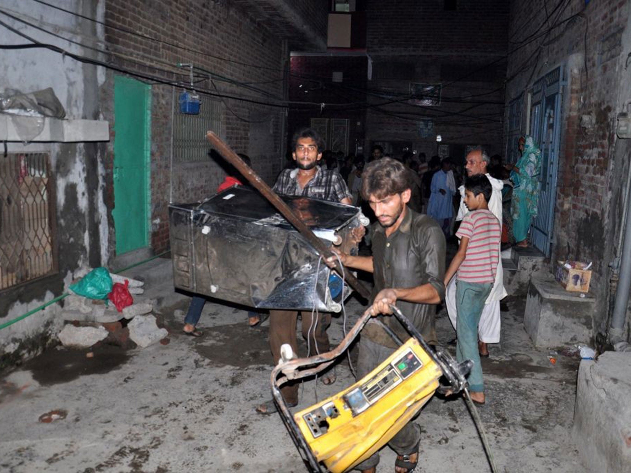 A mob collects the belongings of Ahmadis following accusations of blasphemy, in Gujranwala, Pakistan,