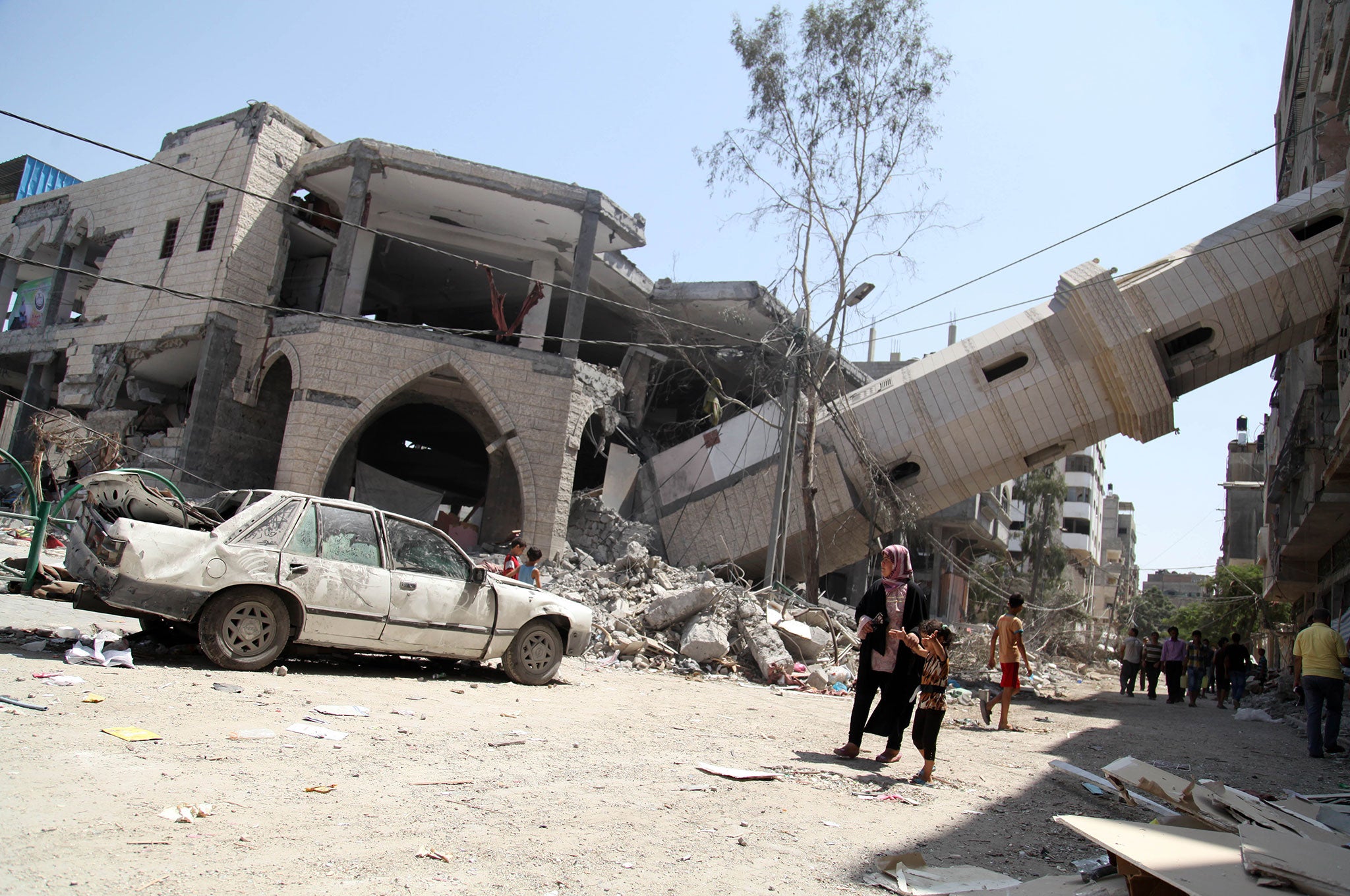 Palestinians walk past the collapsed minaret of a destroyed mosque in Gaza City, after it was hit in an overnight Israeli strike