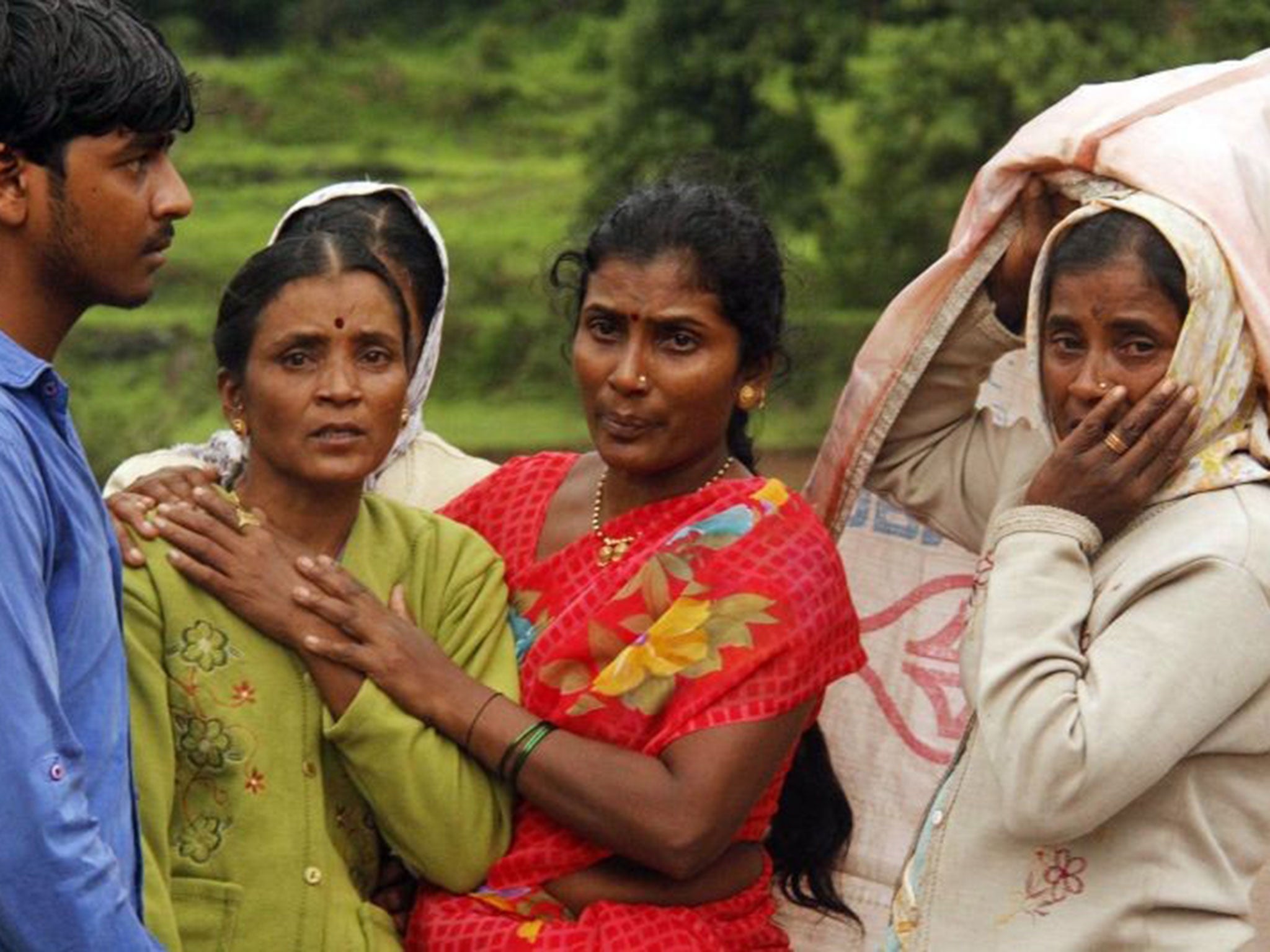 Villagers console each other as they watch a rescue operation at the site of a landslide in Malin village, in the western Indian state of Maharashtra, Wednesday, July 30, 2014.