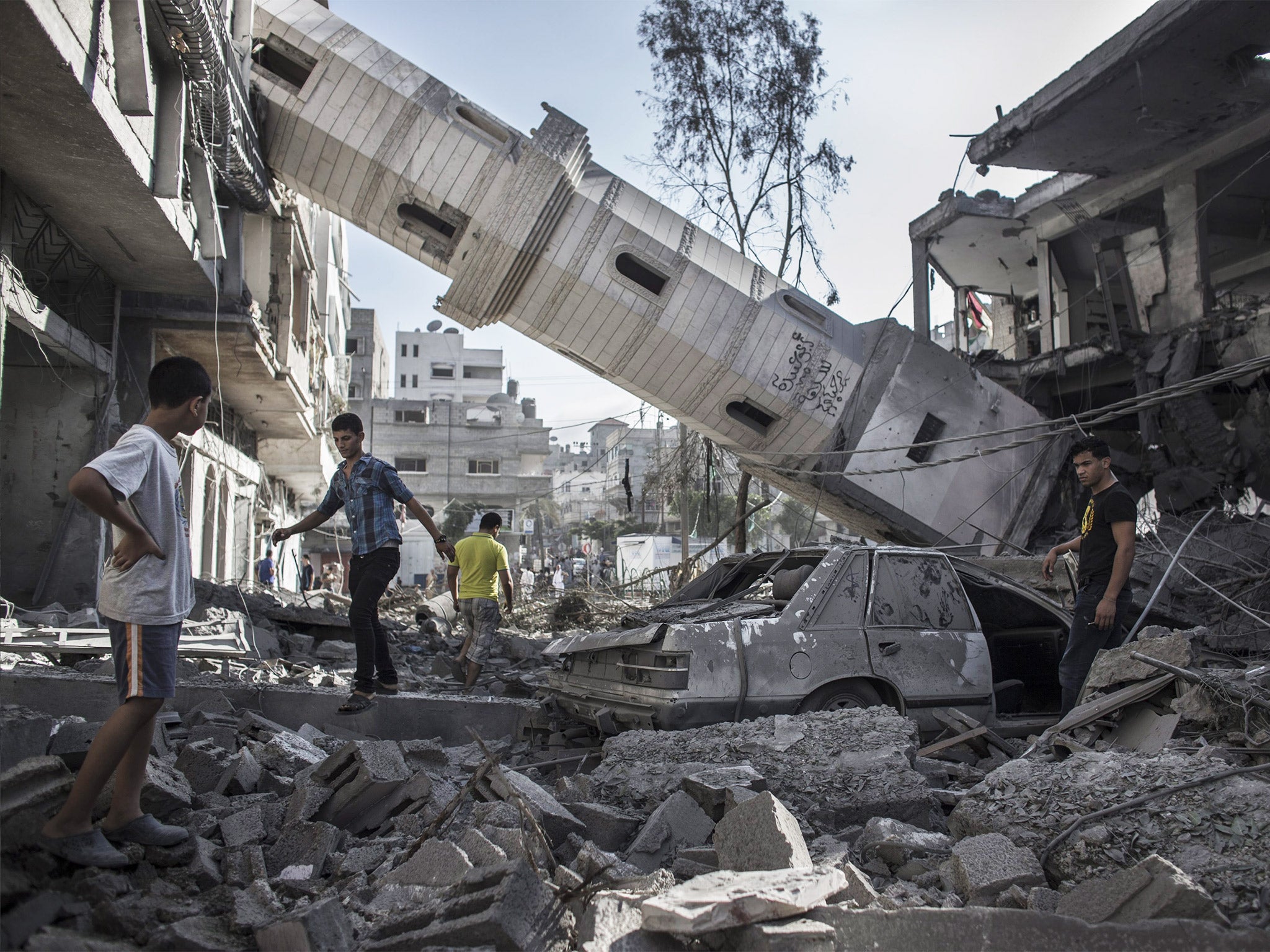 Palestinians walk next to the collapsed minaret of a destroyed mosque in Gaza City. It was destroyed in an overnight Israeli airstrike on Tuesday