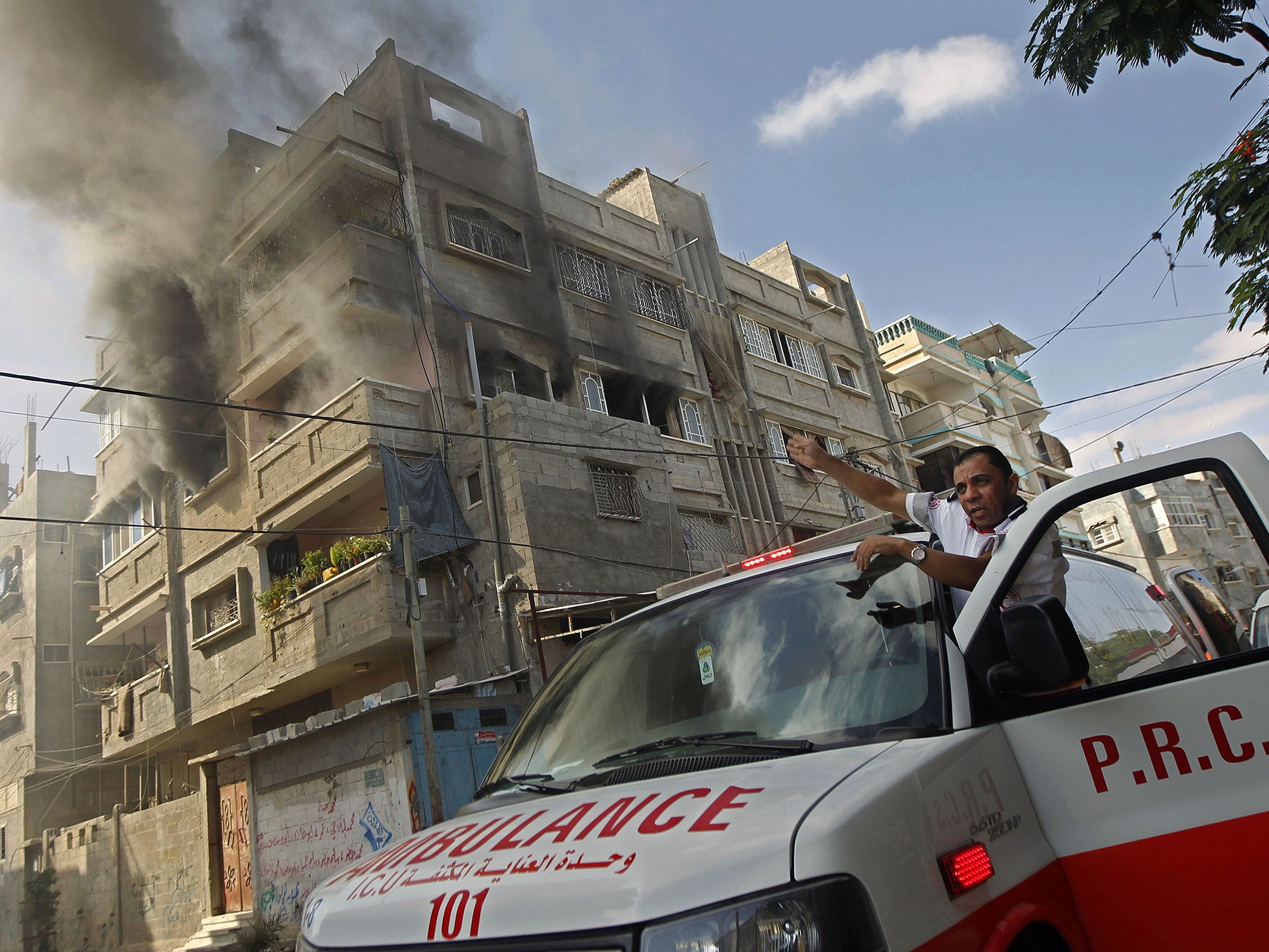 A Red Crescent ambulance driver points at a burning
building in Rafah