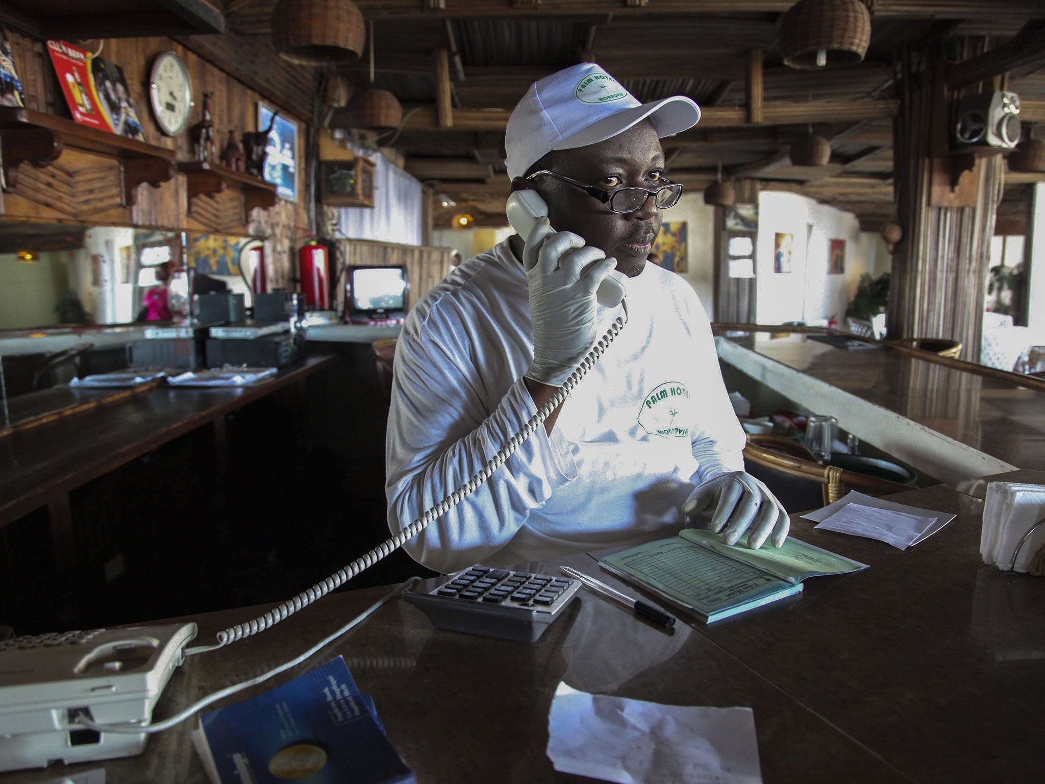 A Liberian receptionist wearing protective gloves to avoid the deadly Ebola virus works at a local hotel in Monrovia, Liberia