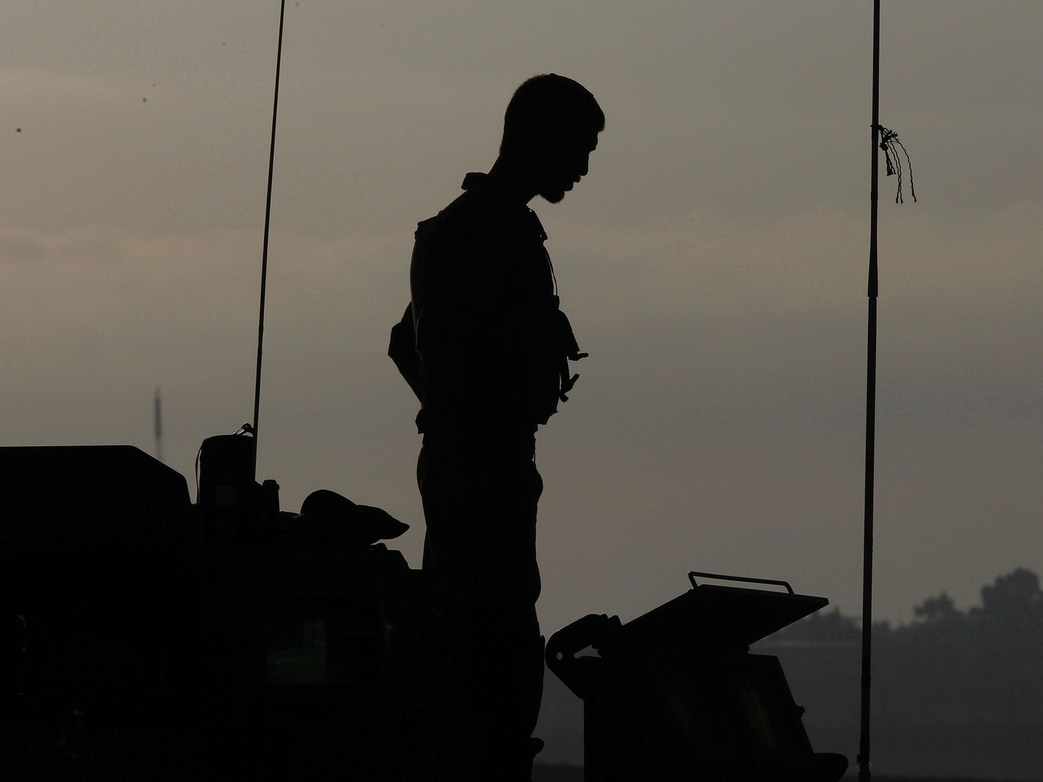 An Israeli soldier stands atop an armoured vehicle