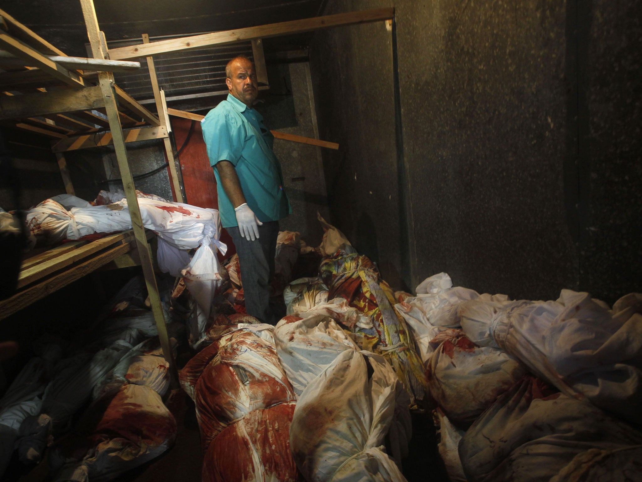 A Palestinian medic stands among bodies in a stored vegetable refrigerator in Rafah, in the southern Gaza Strip