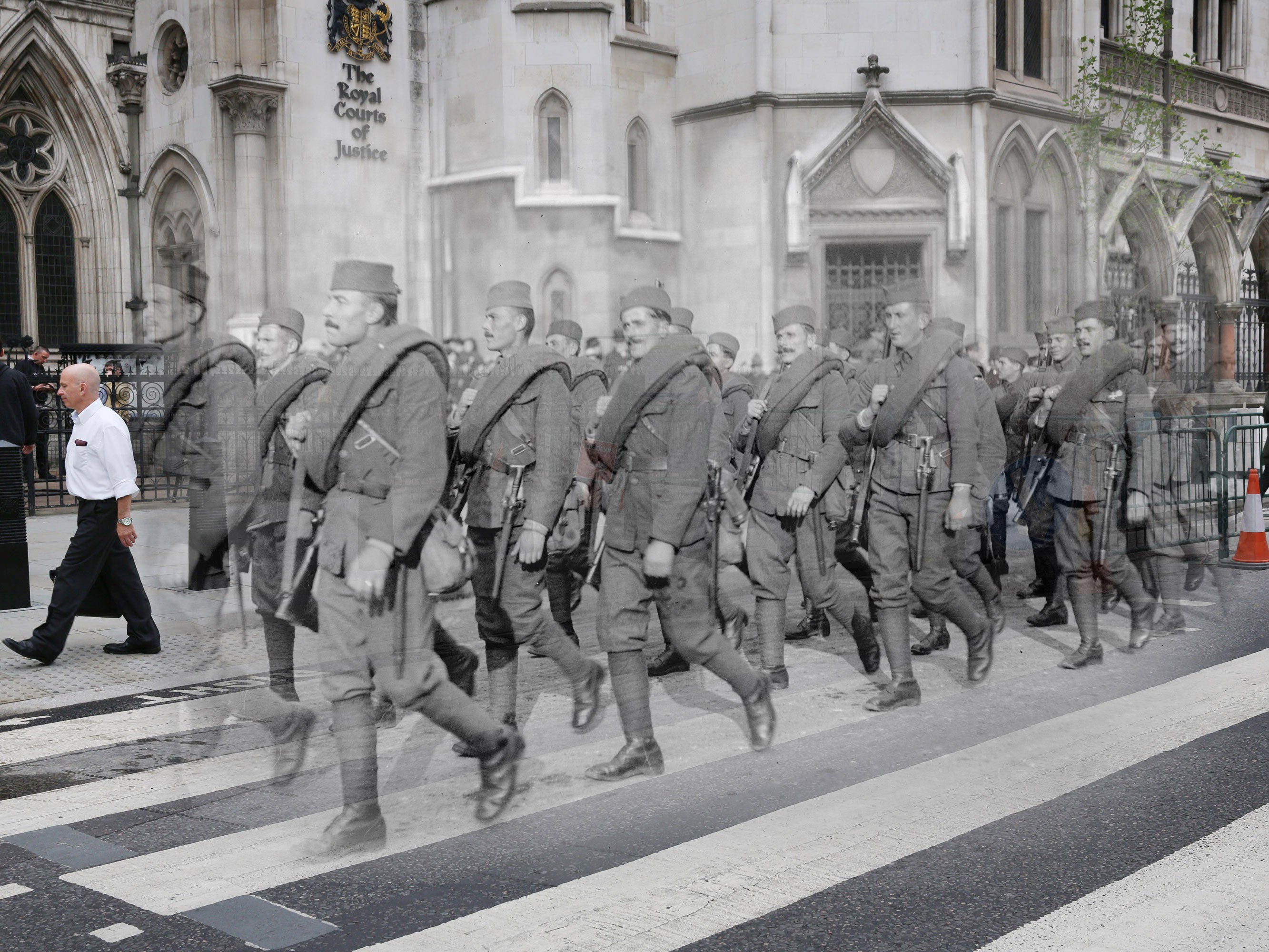 People pass the Royal Courts of Justice next to Serbian soldiers marching in the Lord Mayor's show, London, in the last days of the First World War in November 1918