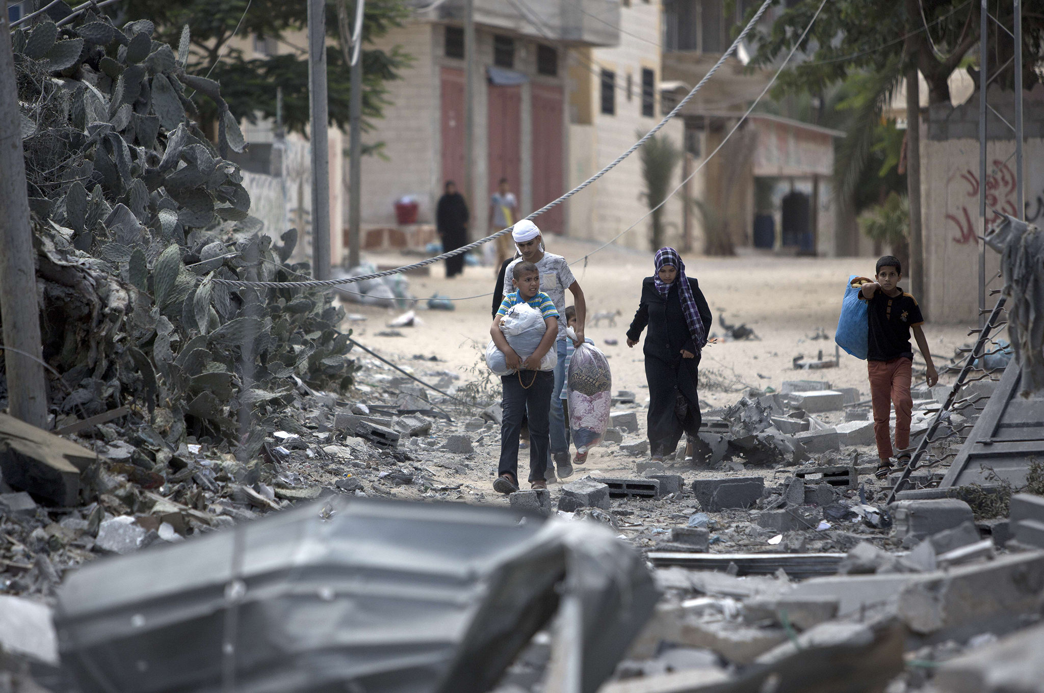 Palestinians carry bags as they return to check on what is left of their homes and businesses following the Israeli military offensive, close to the Rafah refugee camp, in southern Gaza Strip