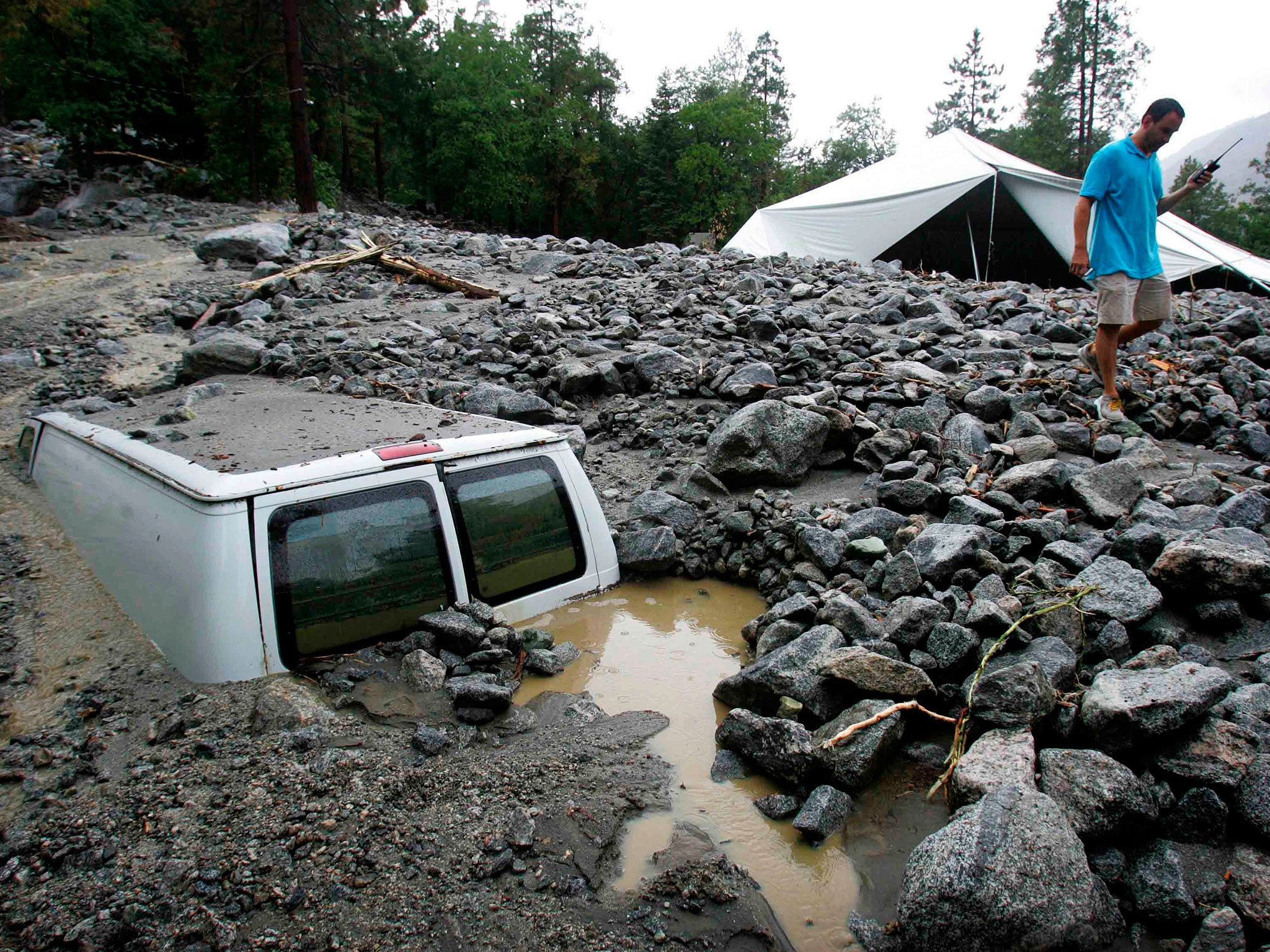 An official of the Forest Home Christian Conference Center in Forest Falls inspects damage on the property following thunderstorms on Sunday