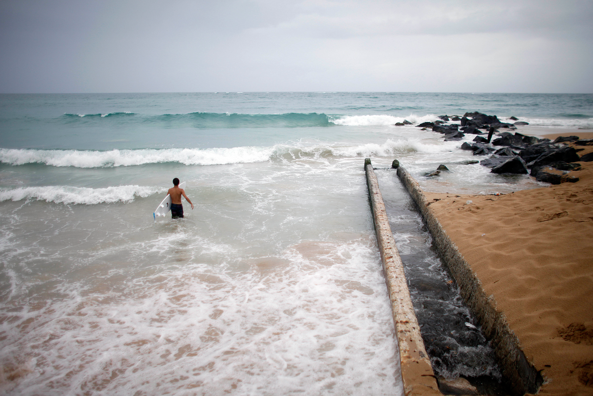 A surfer enters the water to take advantage of the high waves in San Juan, Puerto Rico