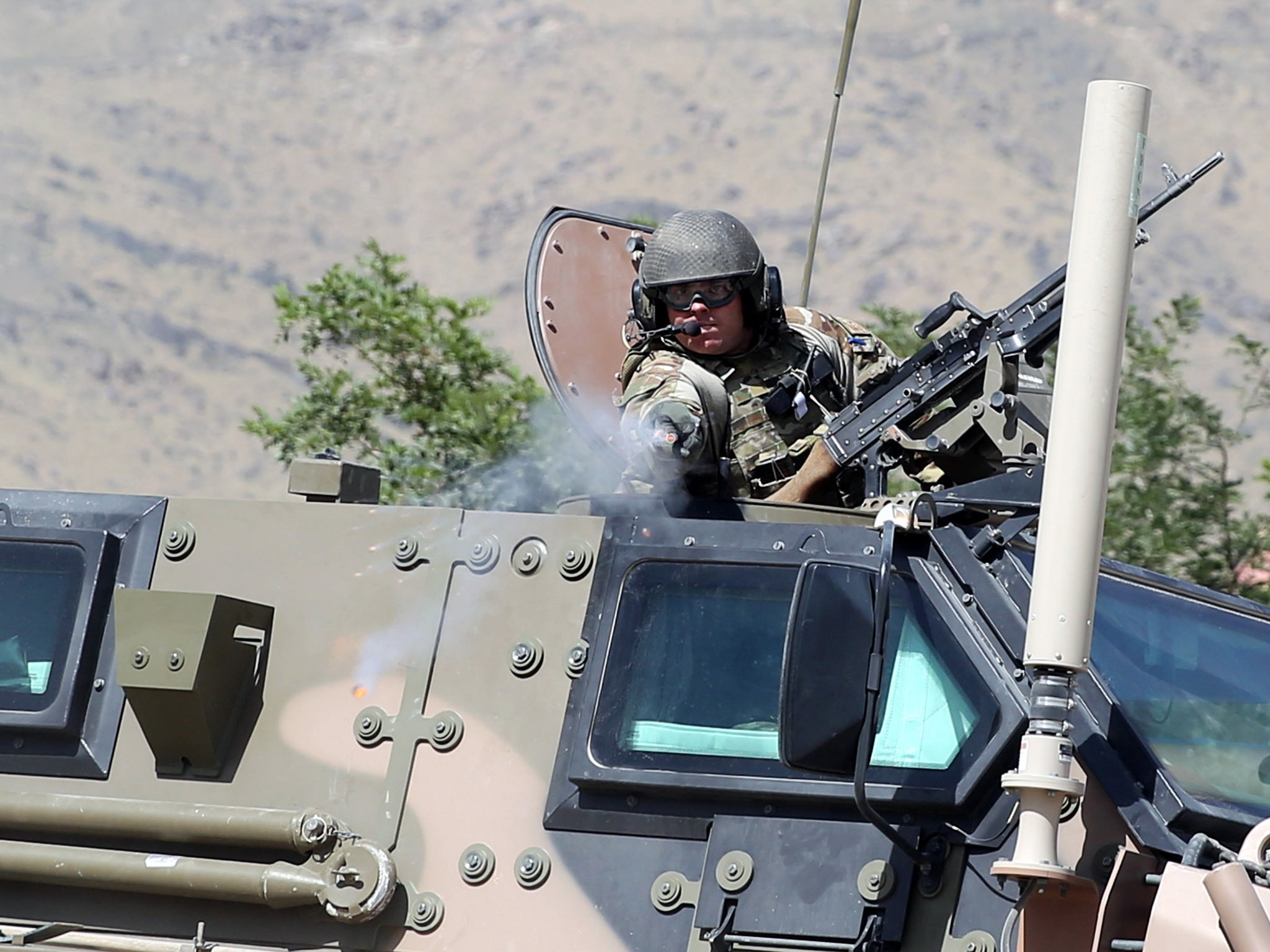 A NATO soldier opens fire in an apparent warning shot in the vicinity of journalists near the main gate of Camp Qargha, west of Kabul, Afghanistan