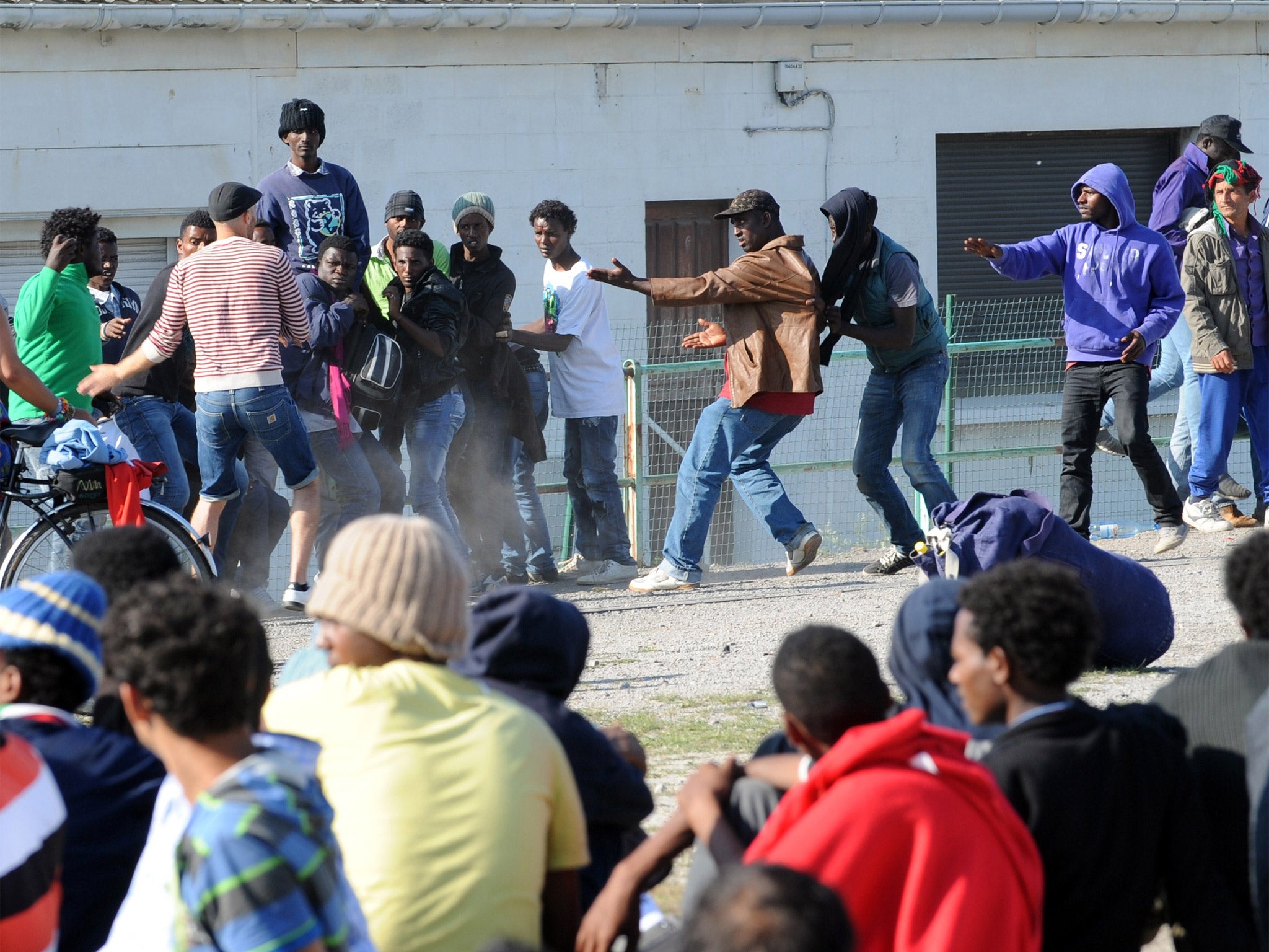 Migrants clash together during a food distribution in Calais (Getty)