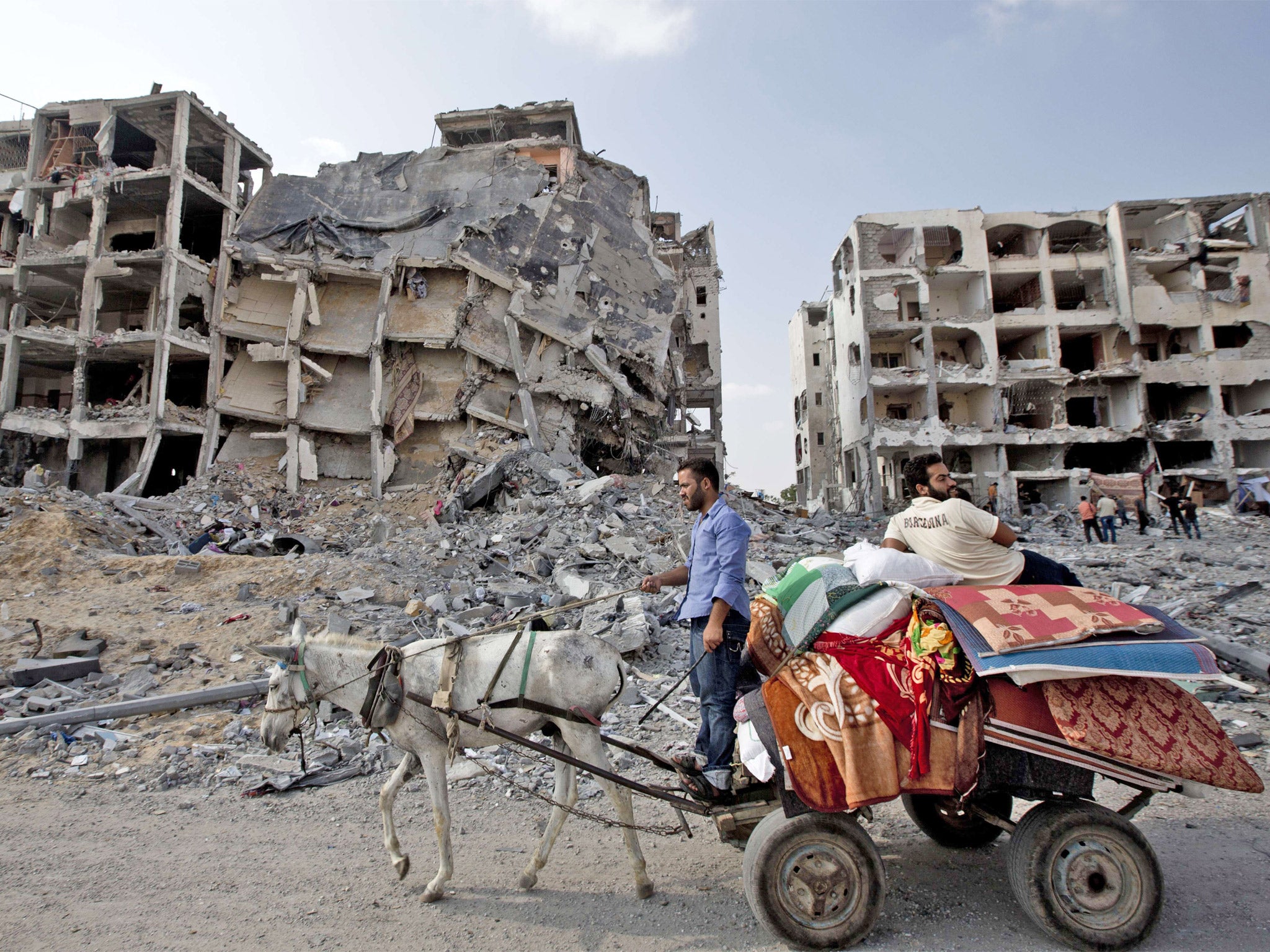 Palestinian men ride a donkey cart past destroyed buildings in the northern Gaza Strip