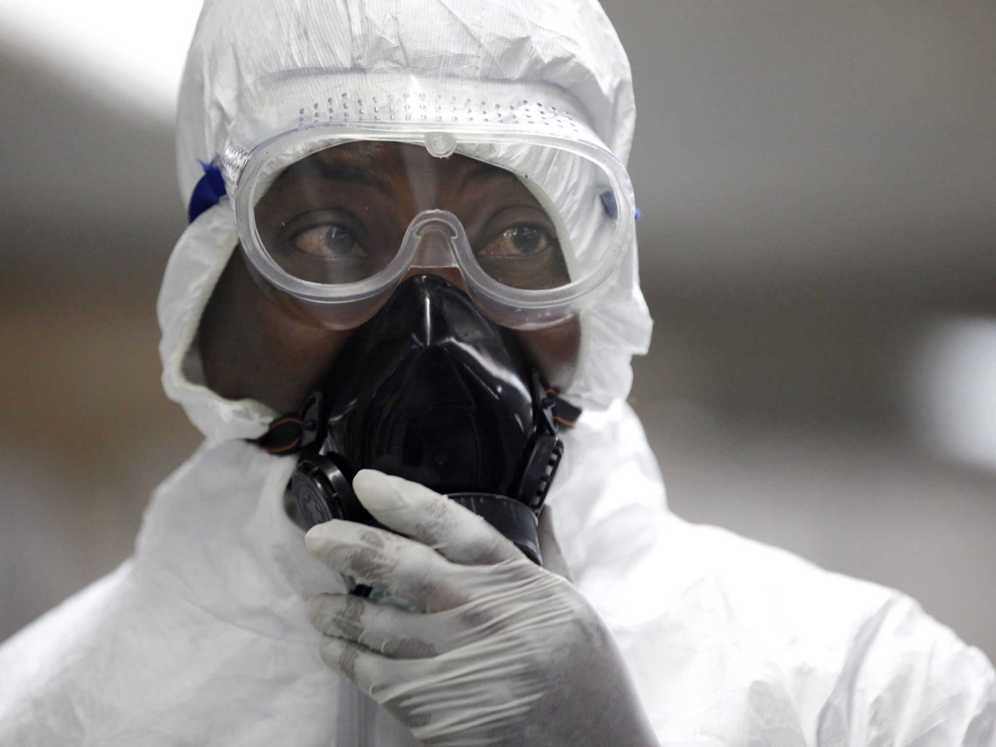 A Nigerian health official wearing a protective suit waits to screen passengers at the arrivals hall in Lagos, Nigeria on 4 August 2014