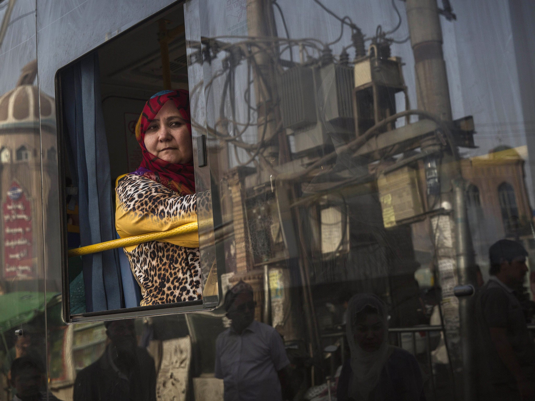 An Uighur woman looks out the window as she rides in a new bus on August 1, 2014 in old Kashgar, Xinjiang Province, China