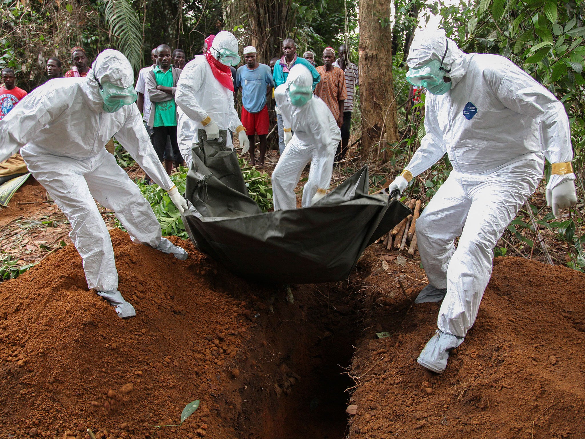 Liberian nurses in protective clothing bury the body of an Ebola victim on the outskirts of Monrovia