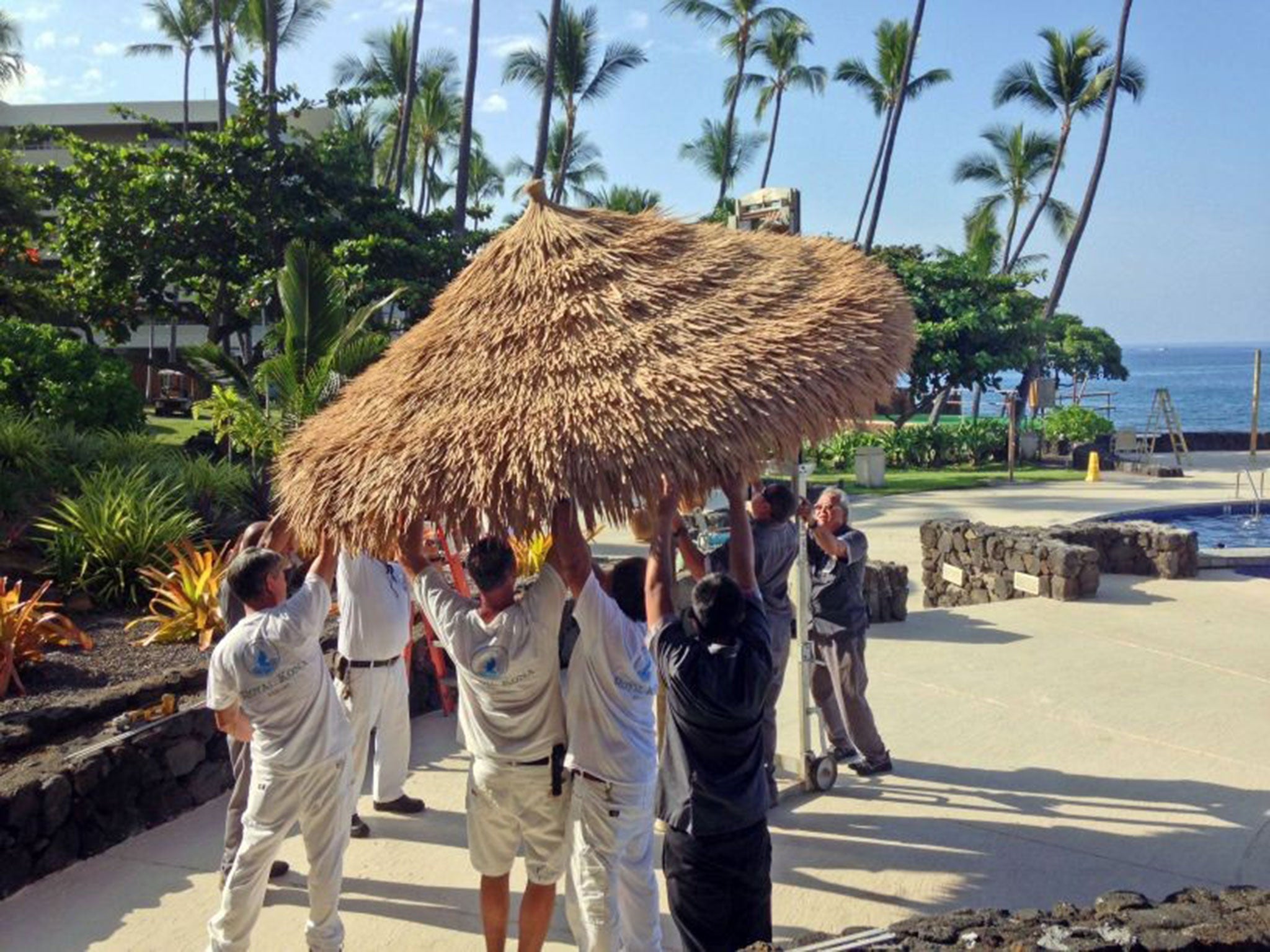 Staff members of the Royal Kona Resort in Kailua, Hawaii take down umbrellas as the resort prepares for Hurricane Iselle