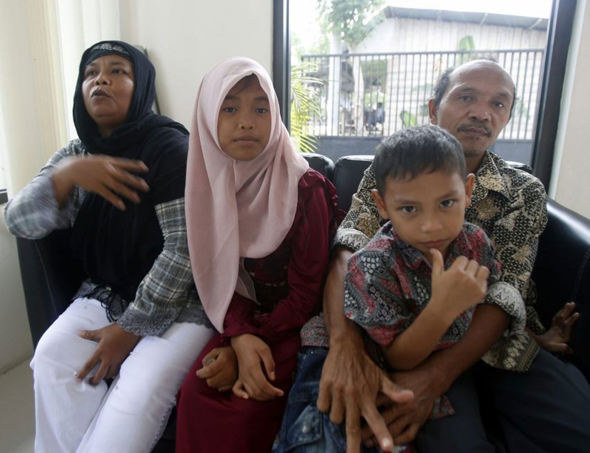 Raudhatul Jannah (2-L), 14, accompanied by her mother, Jamaliah (L) and her father Septi Rangkuti (R) gather as they reunite after ten years in Banda Aceh