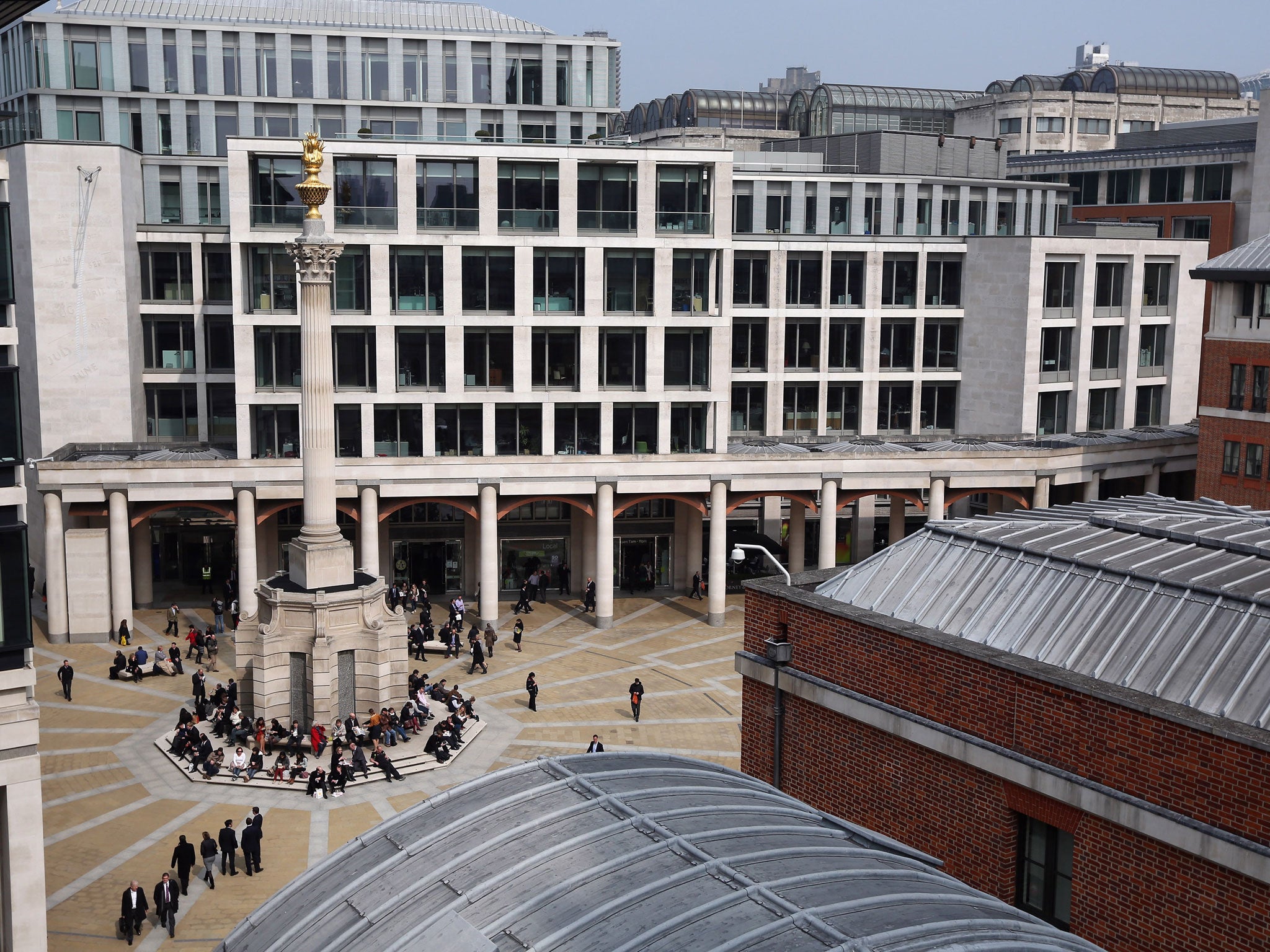 Office workers sit around a monument in Paternoster Square, in front of the London Stock Exchange