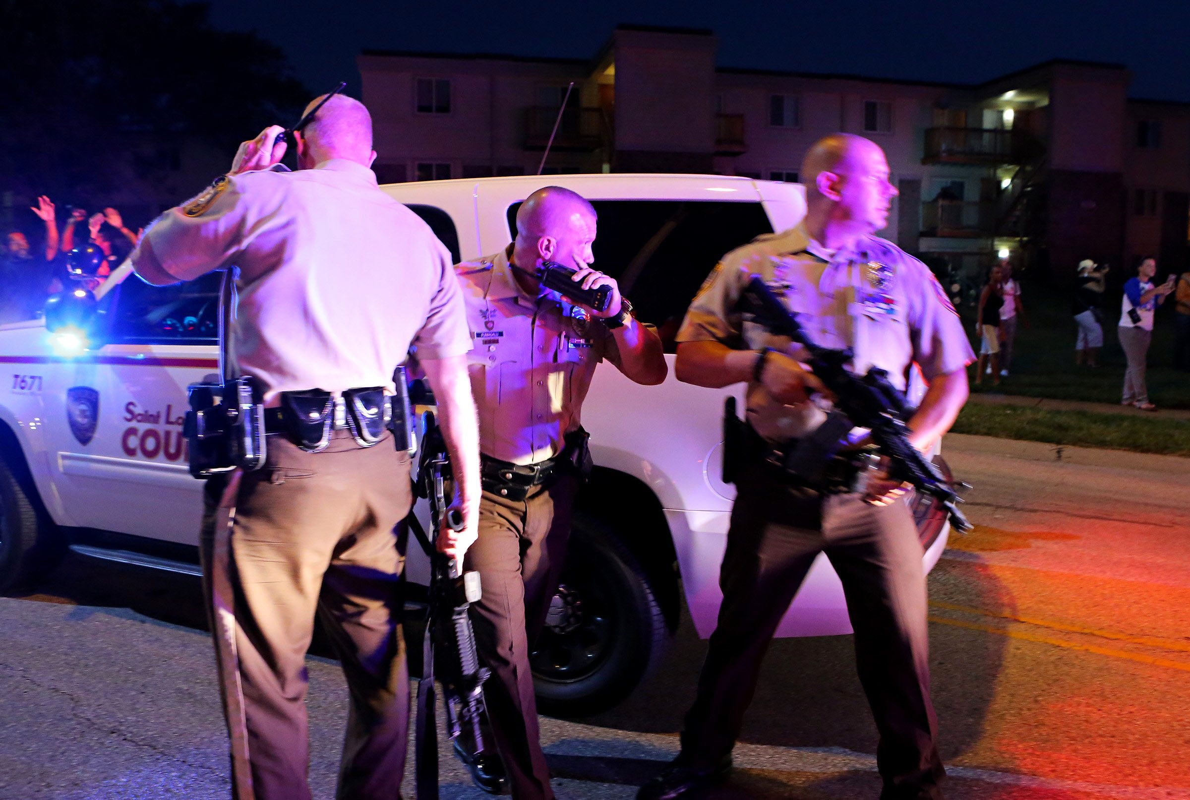 Ferguson police officers try to calm down a crowd near the scene where 18-year-old Michael Brown was fatally shot by police