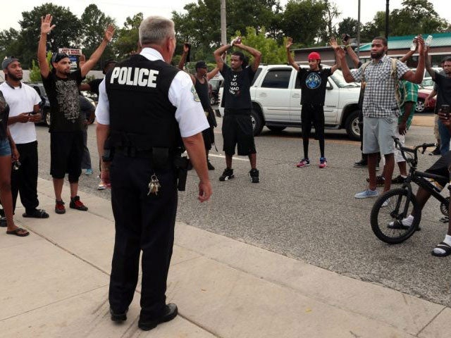 Protesters raise their hands in the 'don't shoot me' stance after being approached by police officers on Sunday