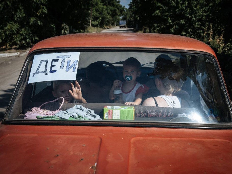 Children look through a car's back windscreen with sign reading 'children', as they drive in Donetsk region on 9 August