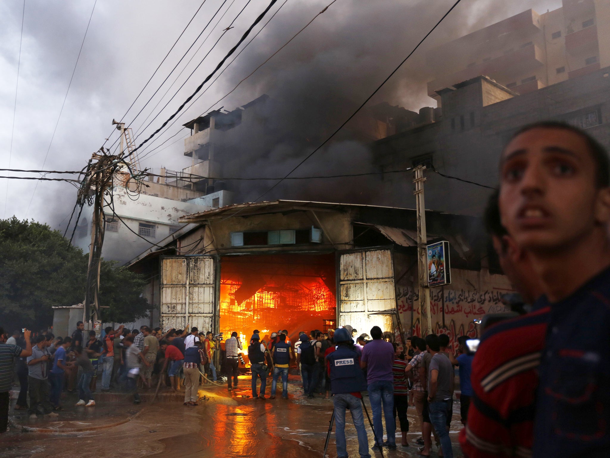 Residents of a neighborhood in Gaza City gather to put out a fire at a soap factory moments after it was hit by an Israeli airstrike