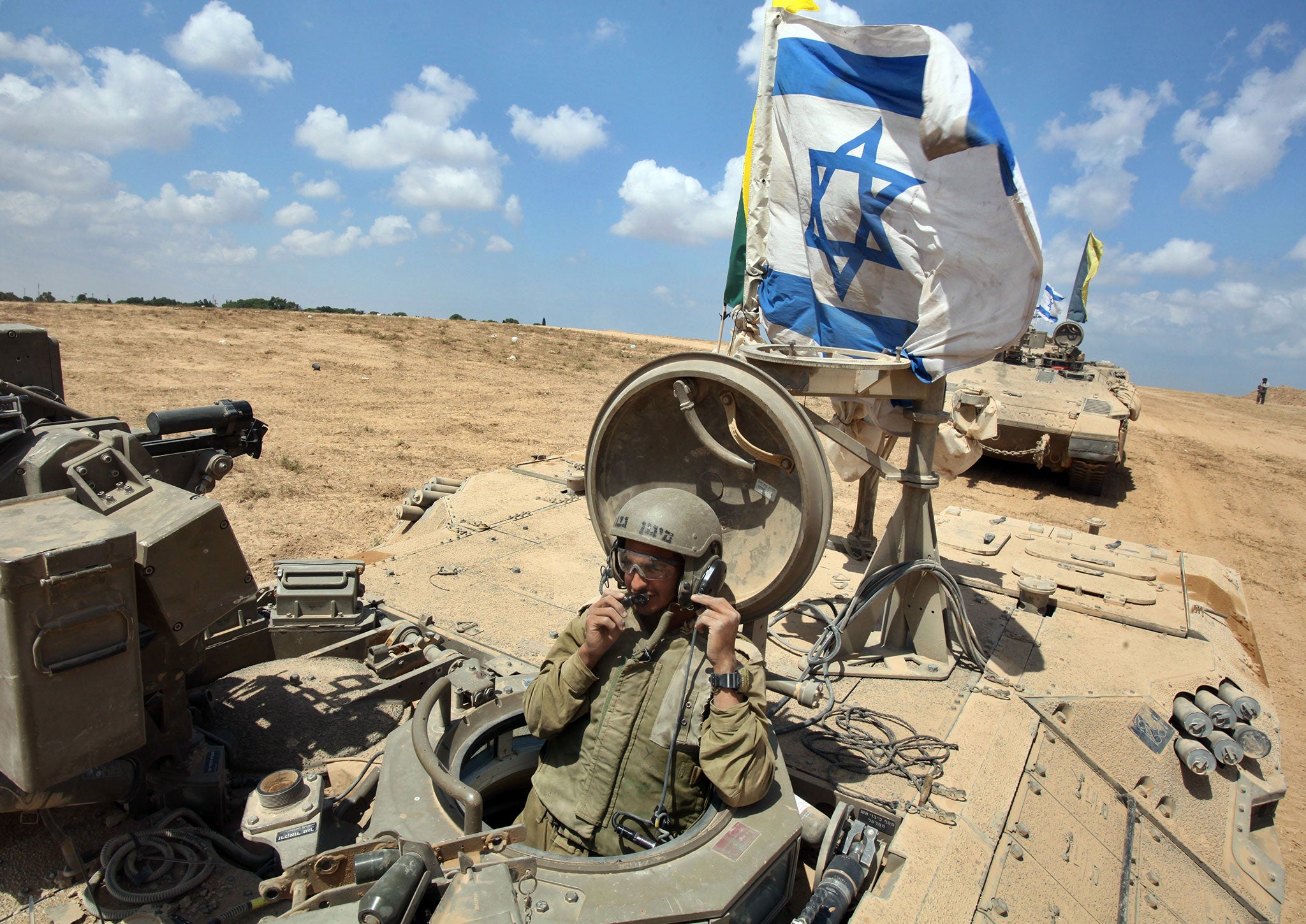 An Israeli soldier sits in an armored personnel carrier (APC) fyling the Israeli flag as they return from the border between Israel and the Gaza Strip