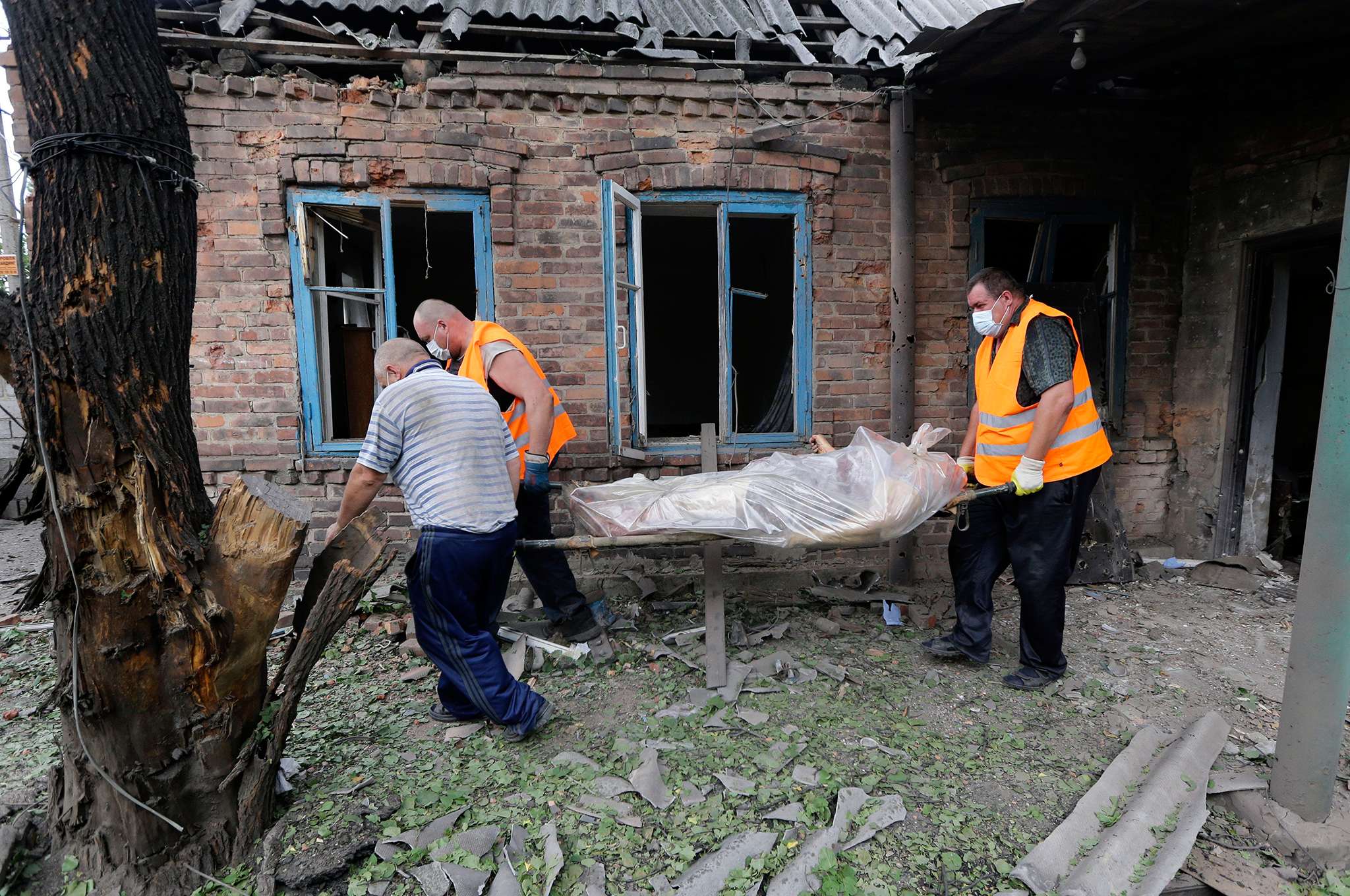 Rescue workers carry the body of woman who was killed during shelling in the Petrovsky district of Donetsk, eastern Ukraine