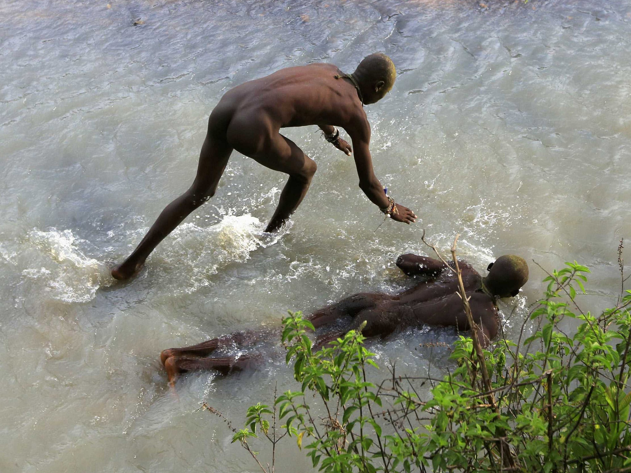 Boys lie in a river to numb themselves before circumcision