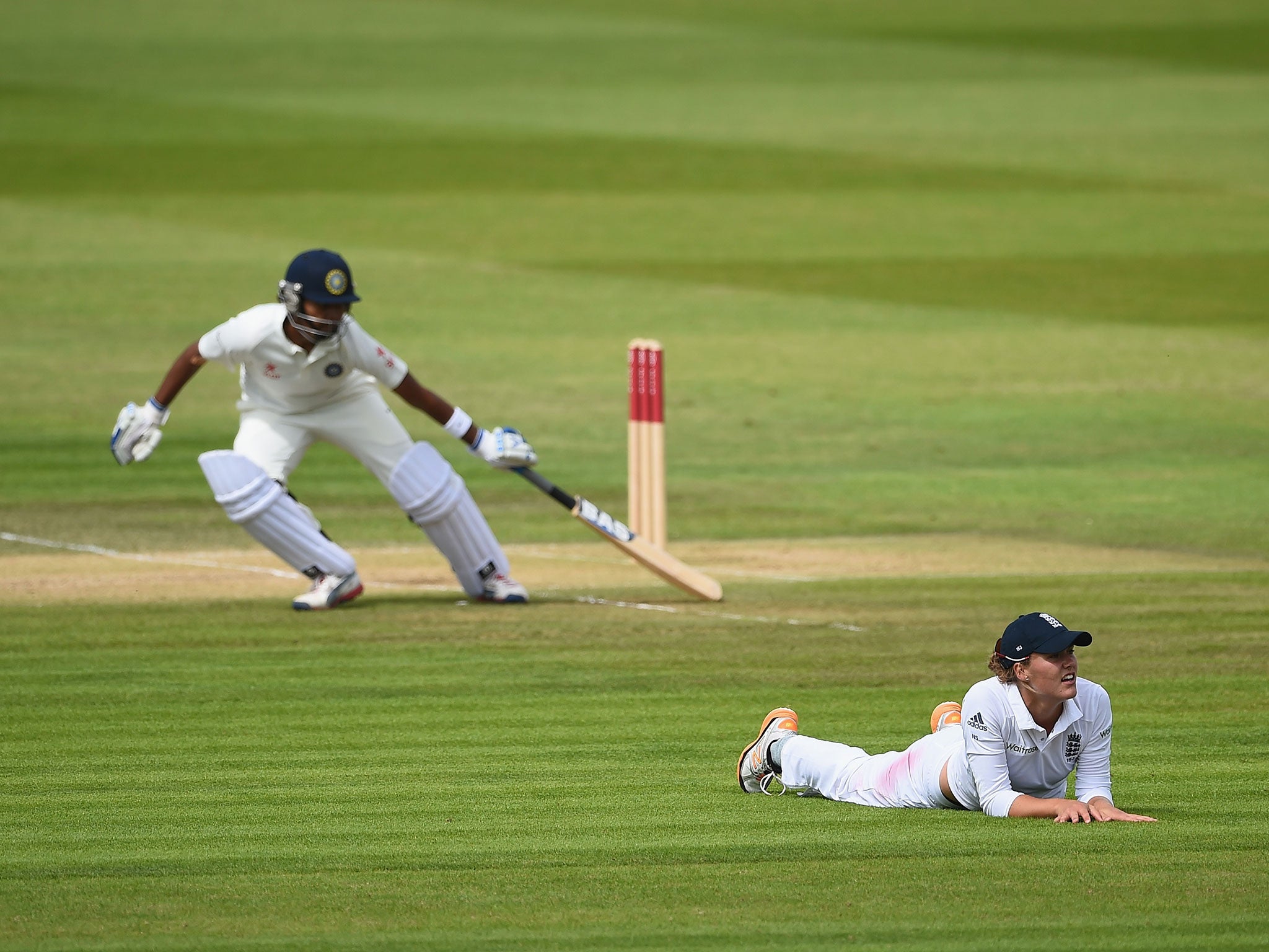 Natalie Sciver of England looks dejected as she lays on the field after a shot by Shikha Pandey of India races past her