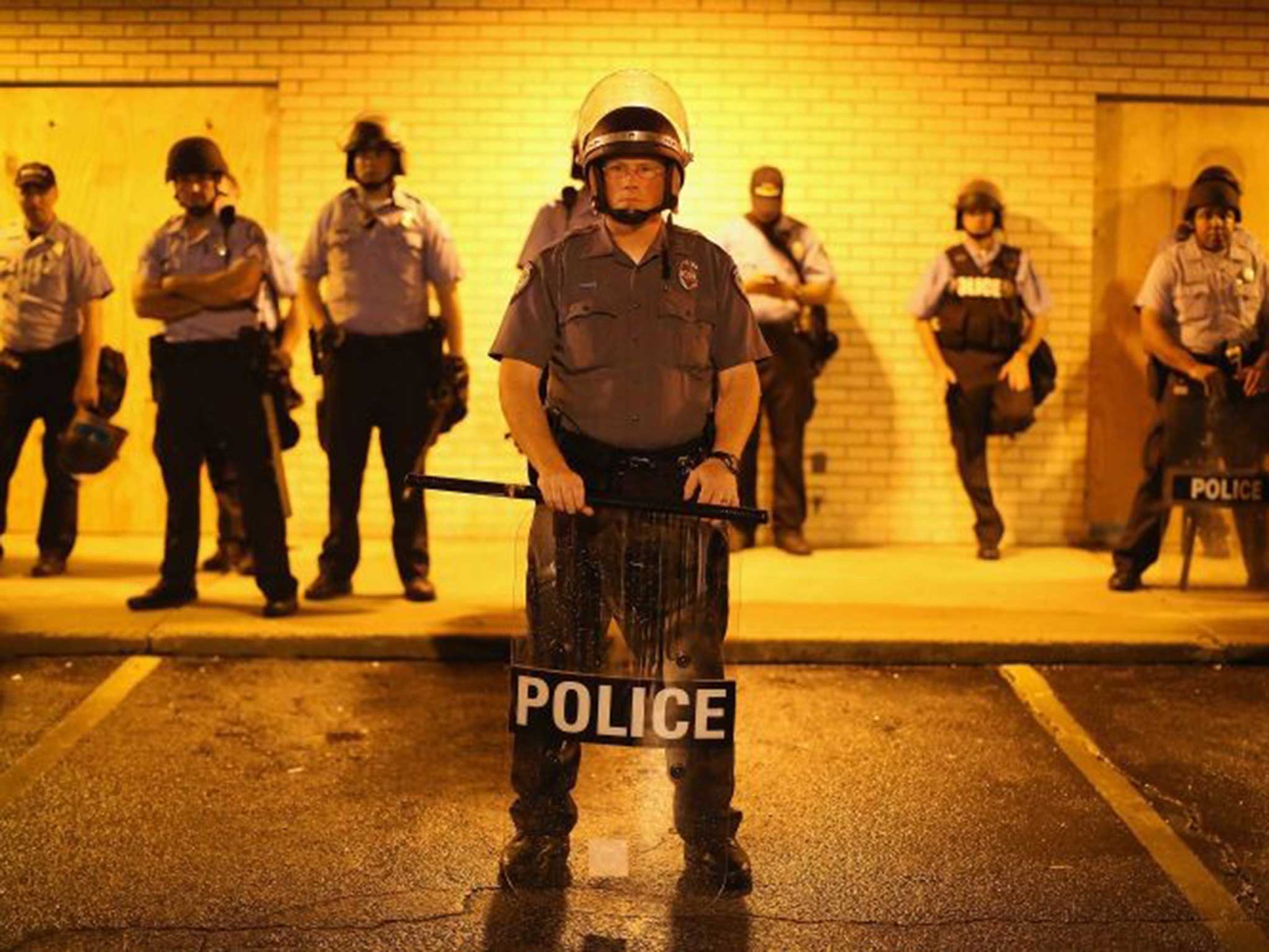 Police stand guard before the mandatory midnight curfew on 16 August