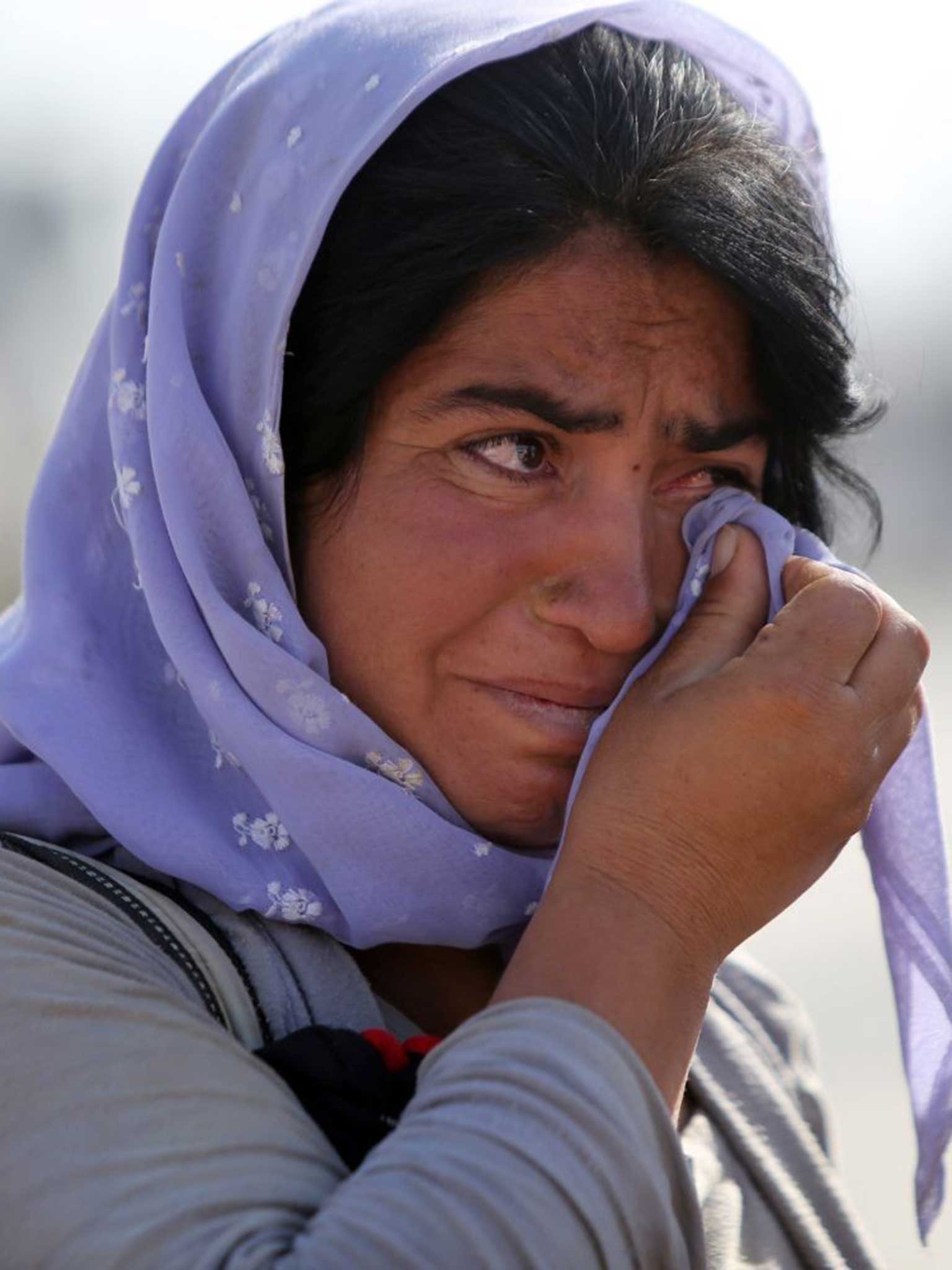 A displaced Iraqi Yazidi woman wipes her eyes at the Bajid Kandala camp near the Tigris River