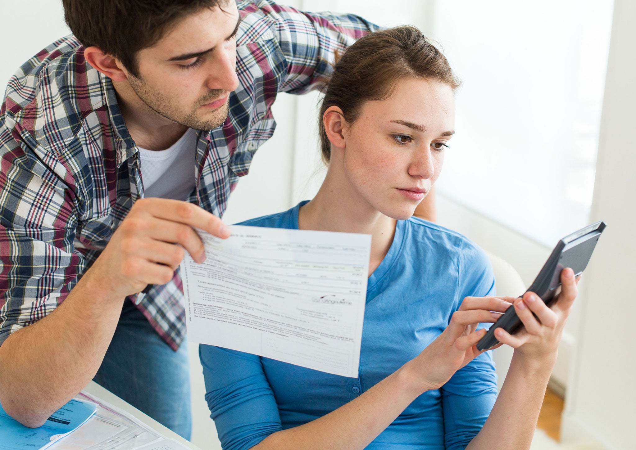 A couple calculates their costs with the help of some paperwork