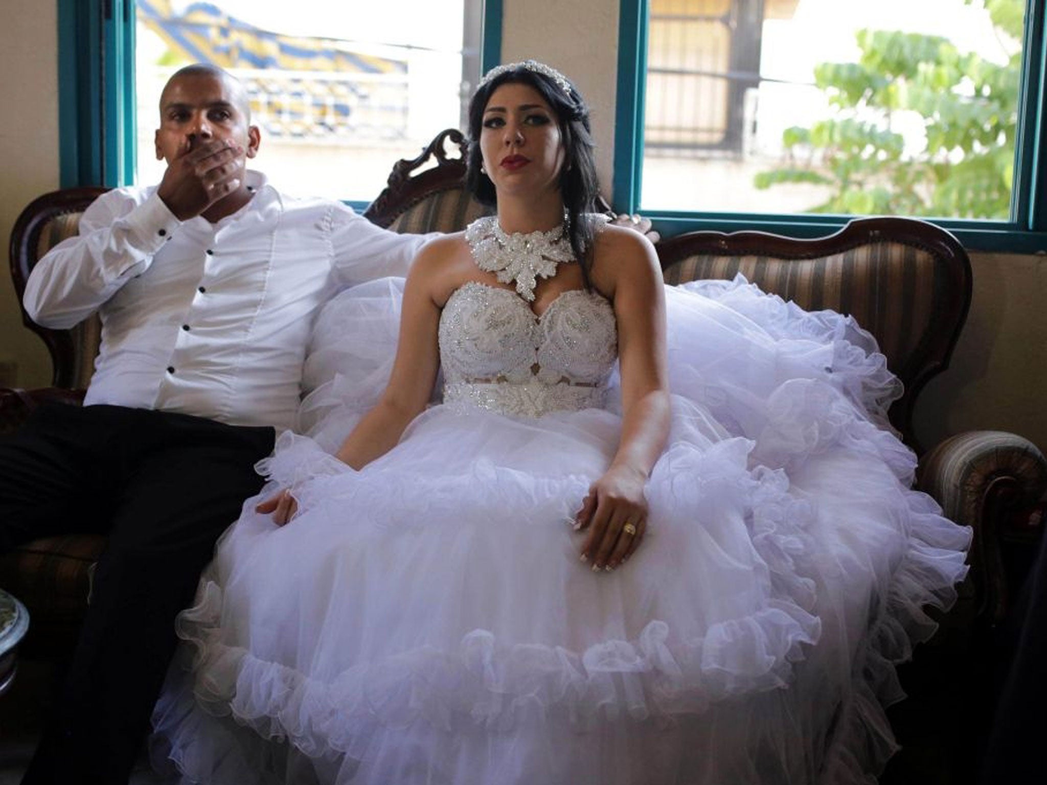 Arab Israeli Muslim groom, Mahmoud Mansour, and his Israeli bride Morel Malcha sit on a couch in Mahmoud's family home in the Jaffa district of Tel Aviv on August 17, 2014, ahead of their wedding ceremony.