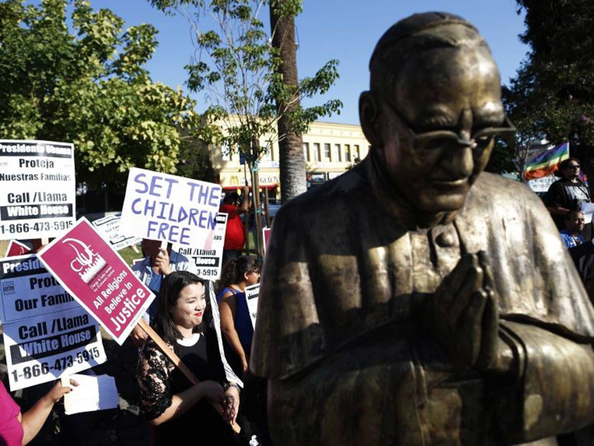 People take part in a vigil for the protection of women and children fleeing violence in Central America by a statue of Archbishop Romero, who was seen as an advocate of the poor