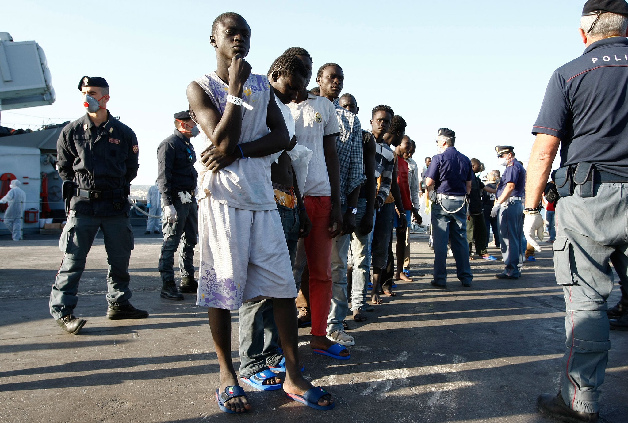 Migrants line up after disembarking from a navy ship in the Sicilian harbour of Pozzallo