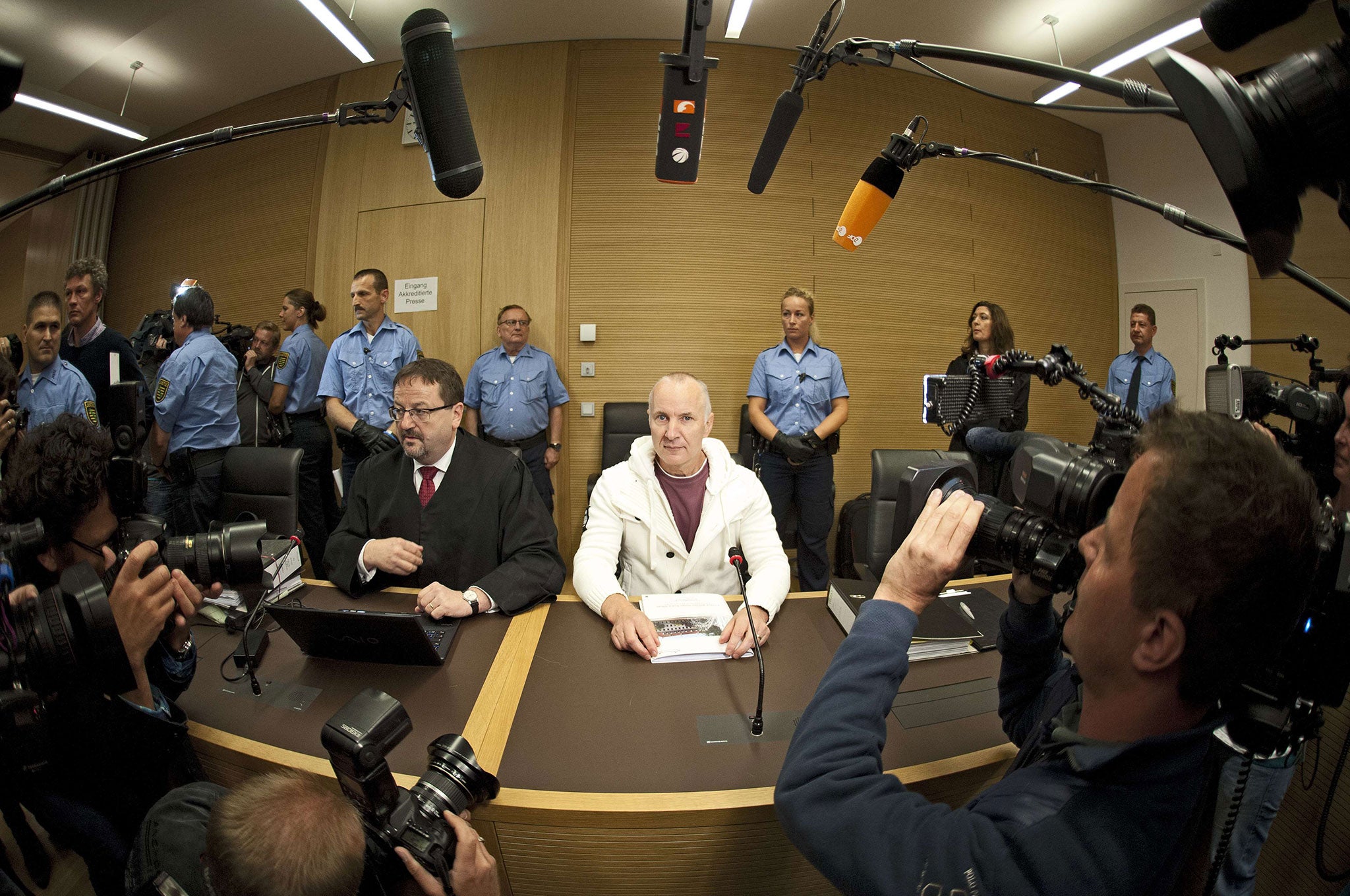 Detlef Guenzel sits next to his lawyer Endrik Wilhelm (C-L) as he waits for the opening of his trial at the court in Dresden, eastern Germany