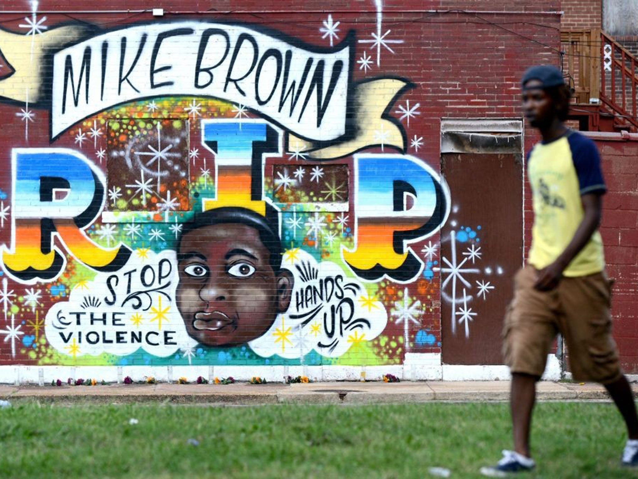 People walk past a mural painted in memory of Michael Brown