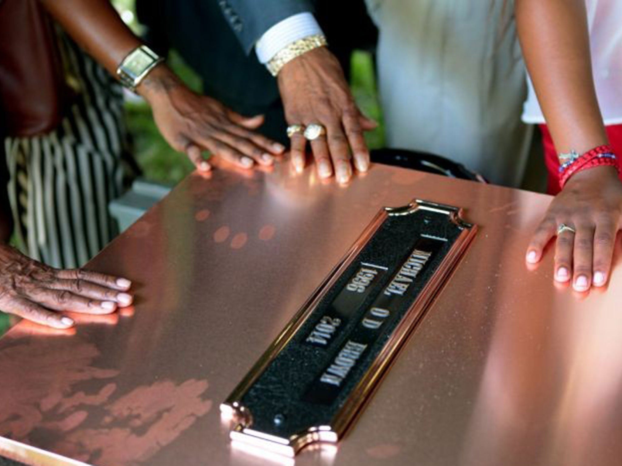 Michael Brown Sr. (C) yells out as the casket is lowered into the ground during the funeral service