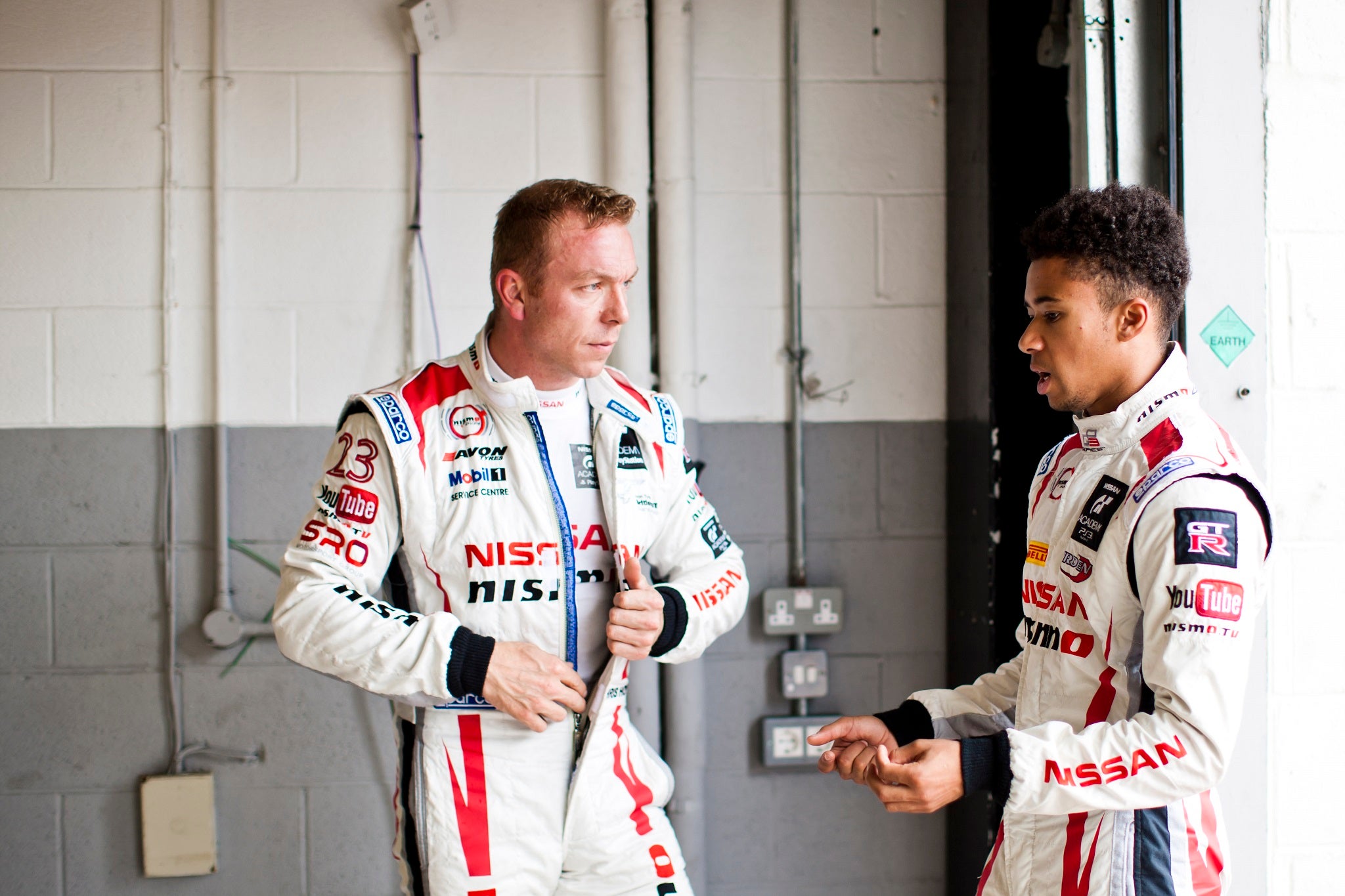 Jann Mardenborough (R) gives Sir Chris Hoy a few tips after a testing session around Silverstone