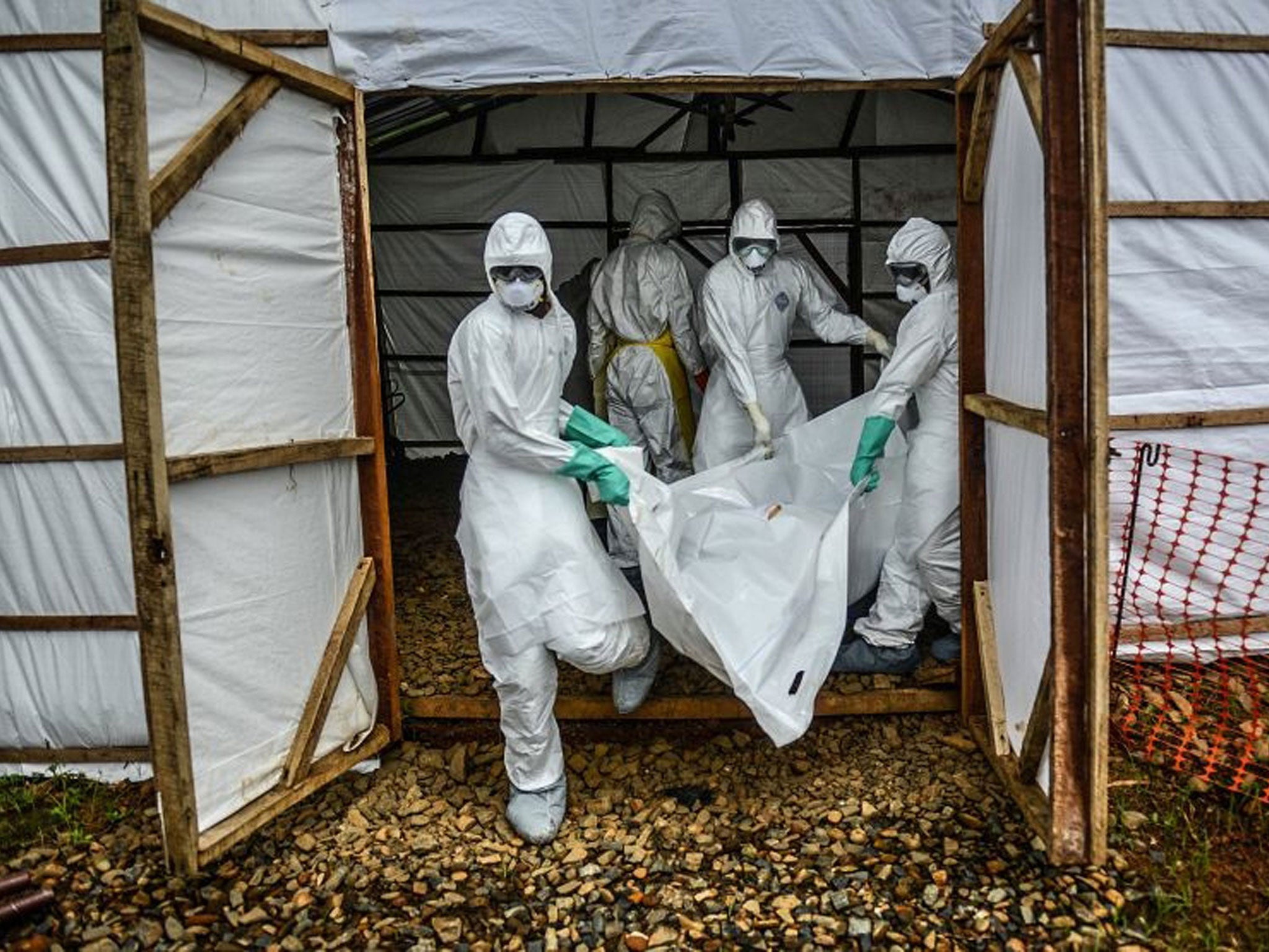 Young volunteers wear carry the bodies of people, sterilized after dying due to the Ebola virus, to a car in Sierra Leone