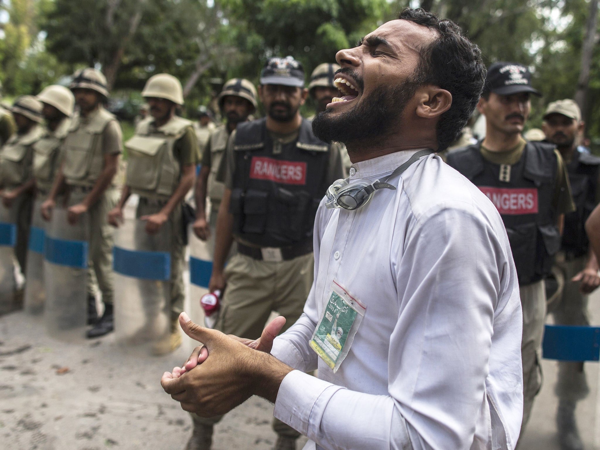 A supporter of Tahir ul-Qadri shouts slogans while soldiers from the Pakistan Rangers block a road leading to Prime Minister Nawaz Sharif's house, during the Revolution March in Islamabad