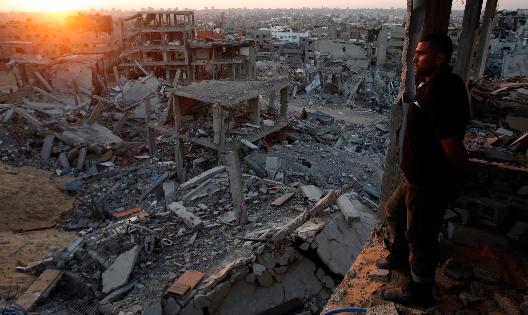 A Palestinian man looks out of his heavily damaged house at neighbouring houses in the east of Gaza City 3 September 2014