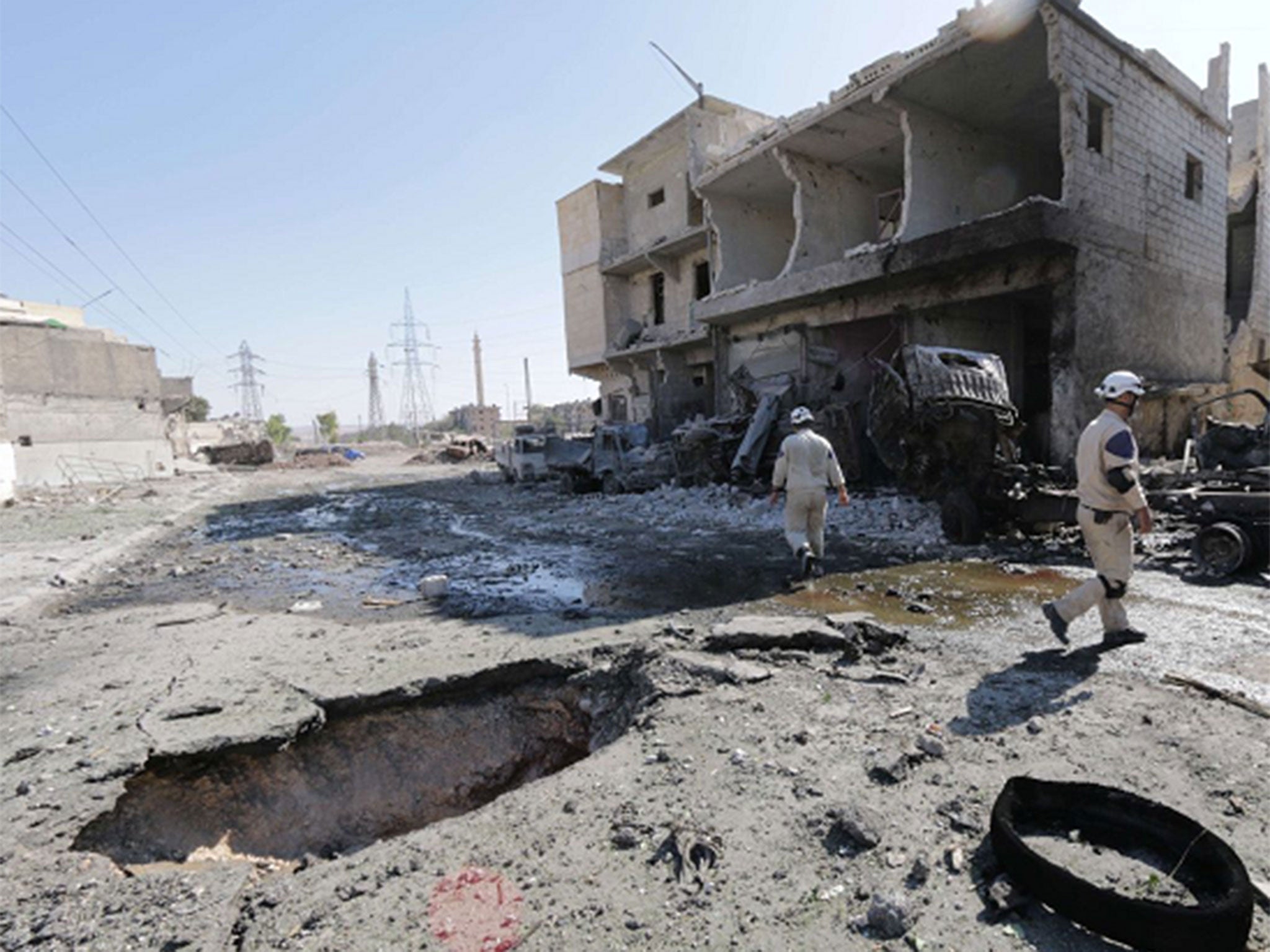 Rescue workers walk past a damaged building following an alleged Syrian government barrel bomb attack in the northern Syrian city of Aleppo