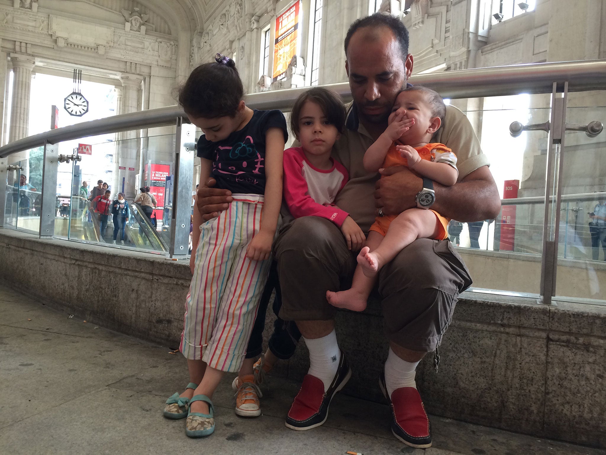 Khaloon Spenati, 30, and his children Mirna, six, and Masa, five and Anas, seven months, at the entrance to Milan Central station, from which he hopes to get to Sweden