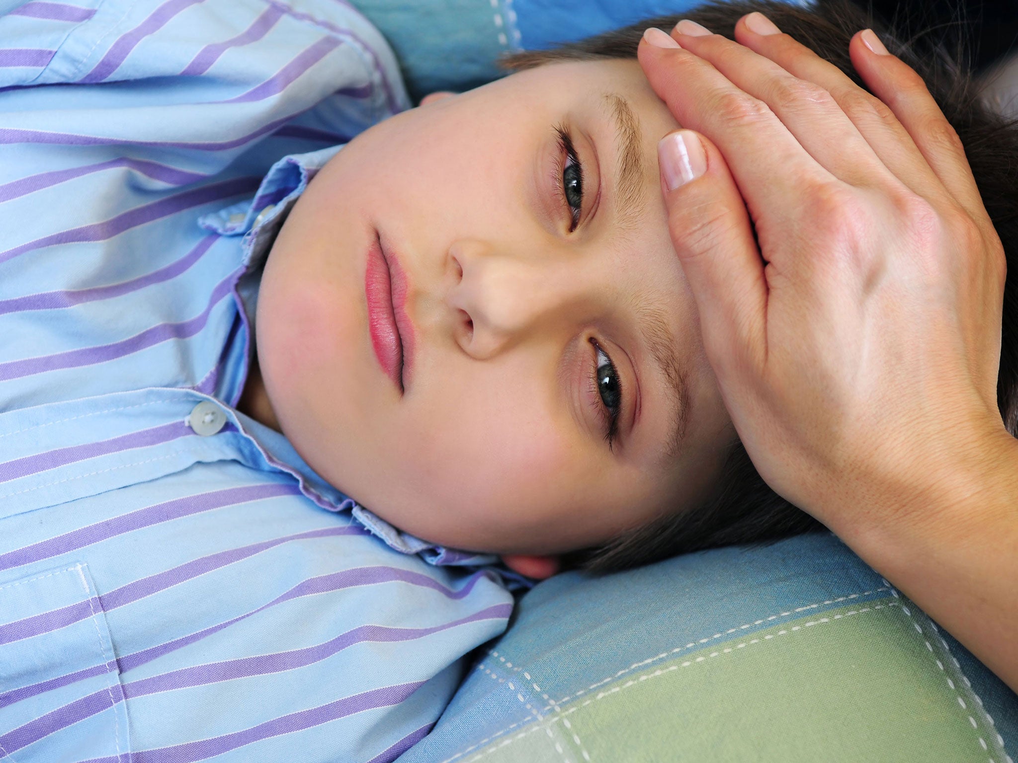 A mother's hand feeling the forehead of a sick child